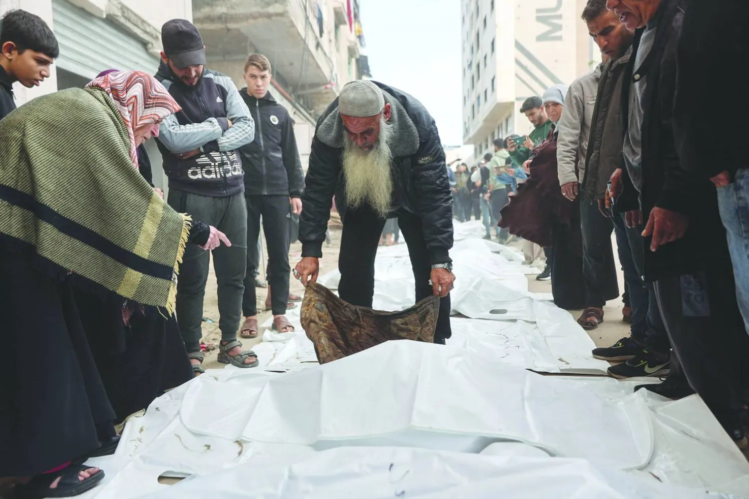 
فلسطينيون يحاولون أمس التعرف على جثث انتُشلت من تحت أنقاض مبنى دُمّر عام 2023 في حي الرمال بمدينة غزة (أ.ف.ب)