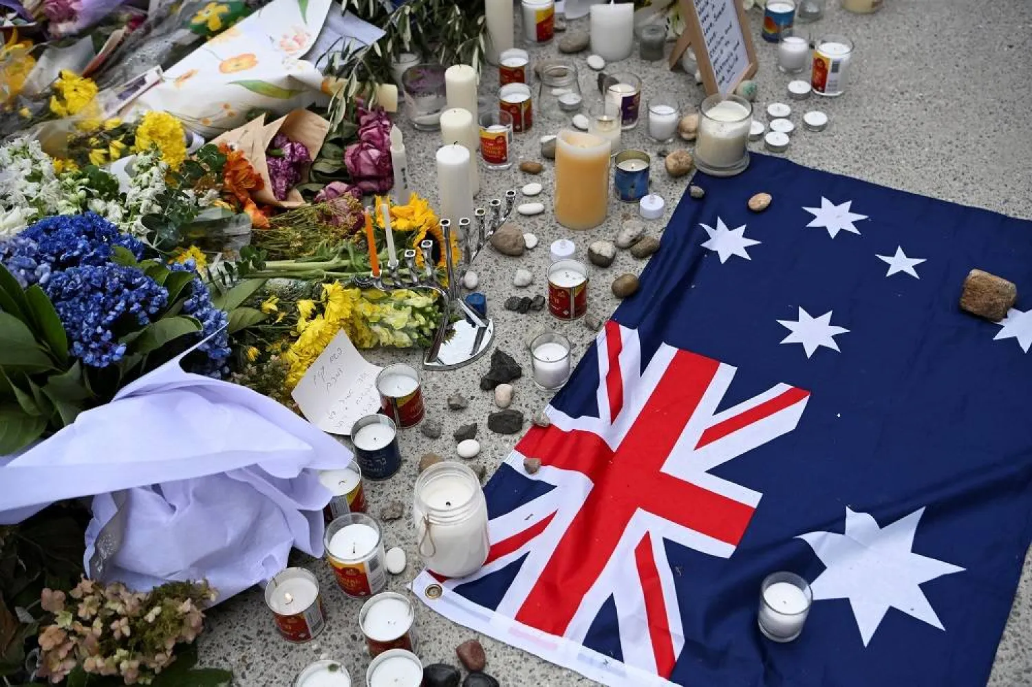 An Australian flag is placed near flowers laid as a tribute at Bondi Beach to honor the victims of a mass shooting that targeted a Hanukkah celebration at Bondi Beach on Sunday, in Sydney, Australia, December 16, 2025. (Reuters)
