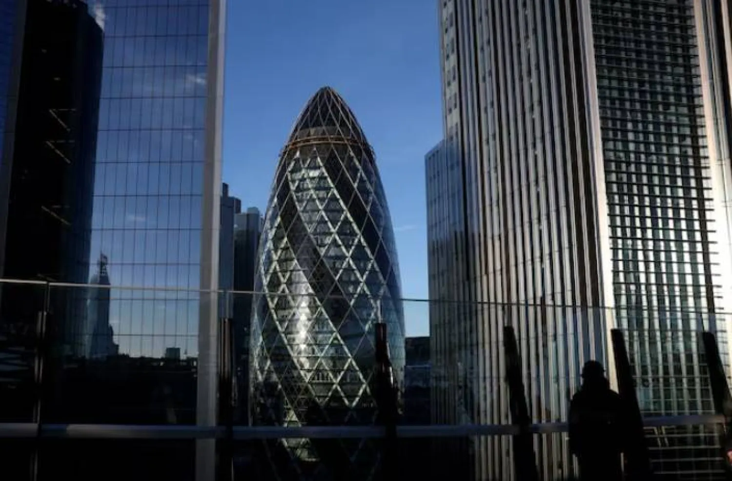 شخص ينظر من حديقة على سطح مبنى في منطقة الأعمال بمدينة لندن (رويترز)