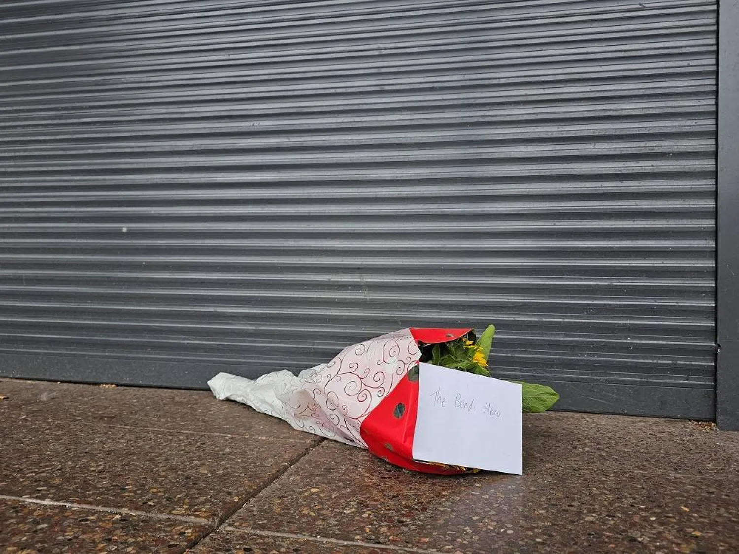 Flowers with a note that read "The Bondi Hero" are left outside tobacco shop owned by Ahmed al-Ahmed, the bystander who is hailed as the "Bondi hero" after he charged at one of the gunmen and seized his rifle during the deadly shooting at Bondi Beach, in Sydney, Australia, December 16, 2025. (Reuters)