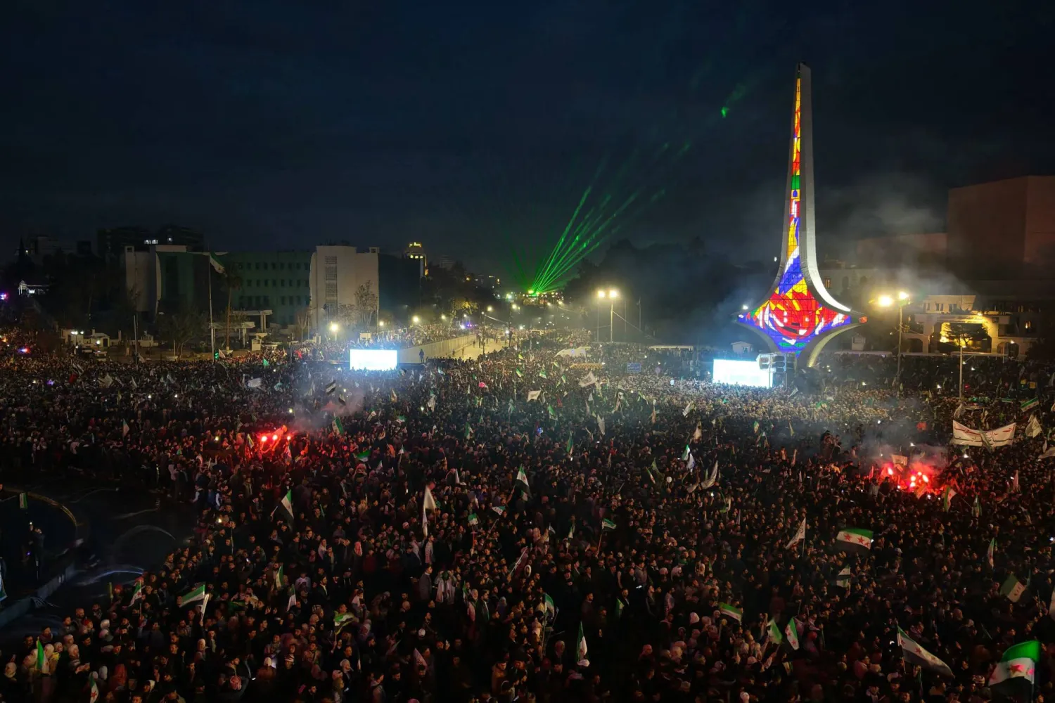 An aerial photograph shows thousands of people celebrating the first anniversary since the ousting of longtime ruler Bashar al-Assad near The Damascus Sword monument in Umayyad Square, in the Syrian capital Damascus on December 8, 2025. (AFP) 
