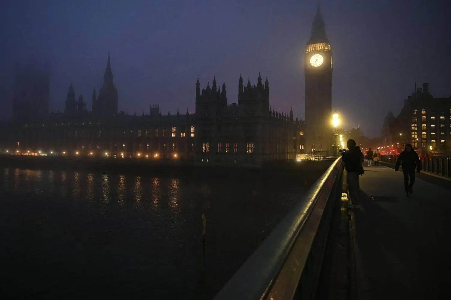 Pedestrians walk across Westminster Bridge as early morning fog covers the streets of London on December 17, 2025. (Photo by JUSTIN TALLIS / AFP)