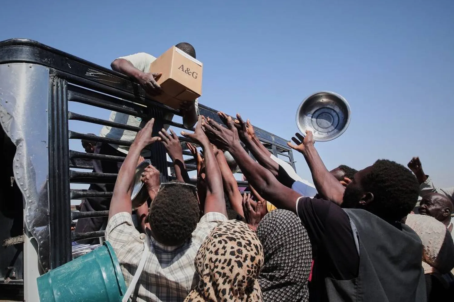 Sudanese families displaced from el-Fasher reach out as aid workers distribute food supplies at the newly established El-Afadh camp in Al Dabbah, in Sudan's Northern State, Sunday, Nov. 16, 2025. (AP)