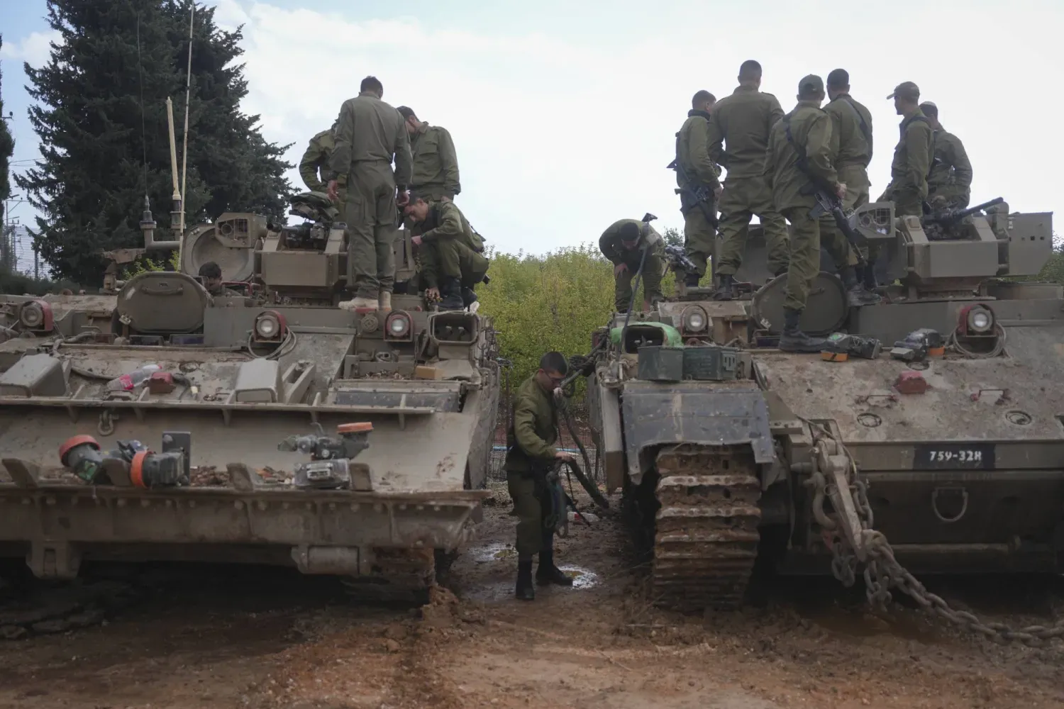 Yukarı Celile'deki Lübnan sınırına yakın Avivim tarım yerleşiminin dışında zırhlı askeri araçların üzerinde oturan İsrail askerleri, 28 Kasım 2024 (AP)