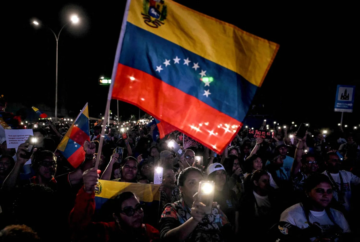 Supporters of Venezuela's President Nicolas Maduro wave a Venezuelan flag during a rally demanding peace in Caracas on December 15, 2025. (Photo by Juan BARRETO / AFP)