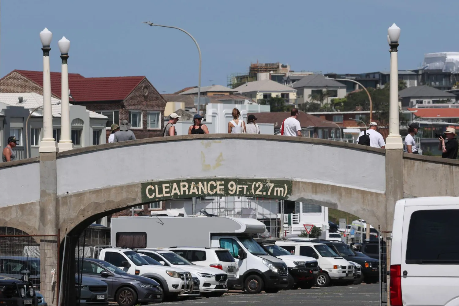 يسير أشخاص عبر جسر المشاة الذي استخدمه المسلحان الأب وابنه خلال إطلاق النار على شاطئ بونداي في 14 ديسمبر (أ.ف.ب)