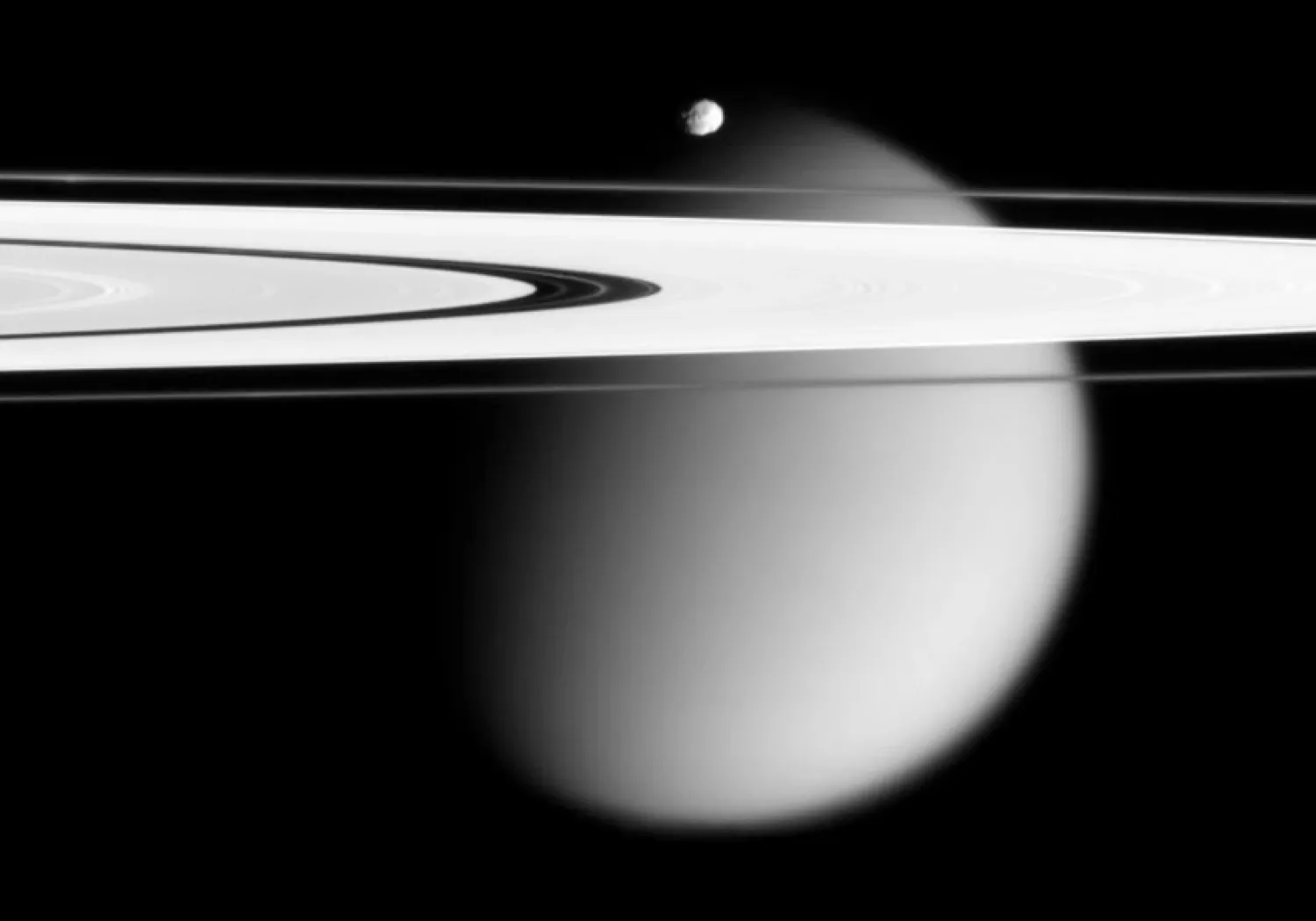 This image made by the Cassini spacecraft and provided by NASA on March 12, 2006, shows two of Saturn's moons, the small Epimetheus and smog-enshrouded Titan, with Saturn's A and F rings stretching across the frame. (NASA via AP)