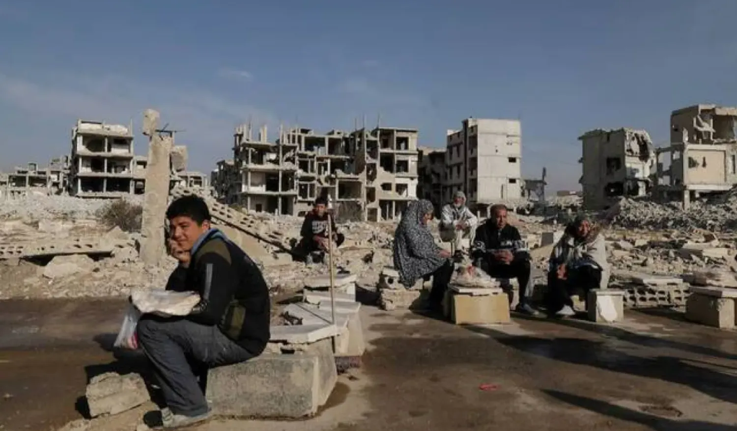 People sit after receiving bread from Ecir Kapici, Turkish humanitarian NGO at Al-Yarmouk Palestinian refugee camp, after Syria's Bashar Al-Assad was ousted, in Damascus, Syria, December 20 , 2024. (Reuters)
