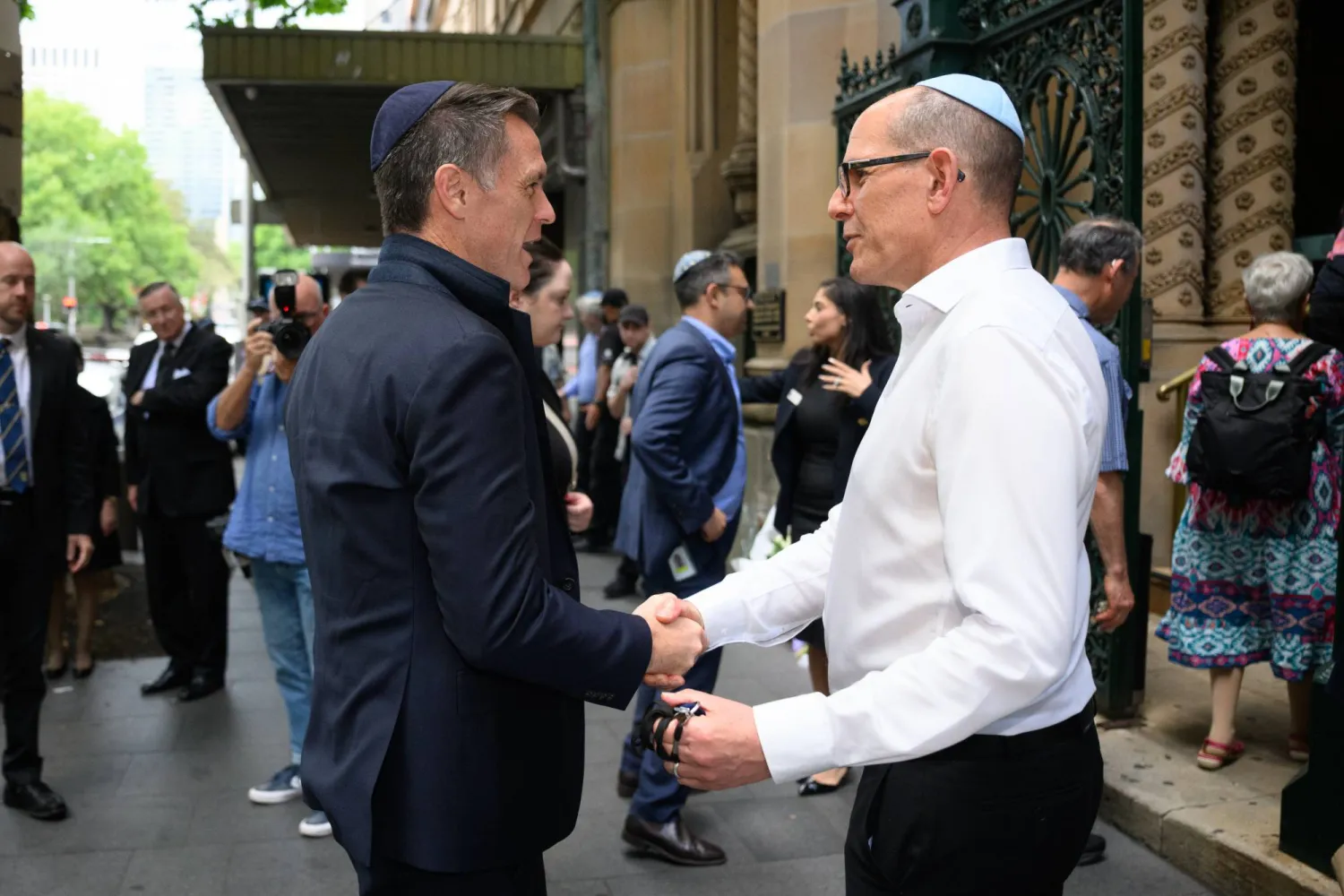 استقبل لاري دورفان المدير العام لكنيس غريت رئيس وزراء ولاية نيو ساوث ويلز كريس مينز لدى وصوله إلى الكنيس في سيدني 19 ديسمبر 2025 (إ.ب.أ)