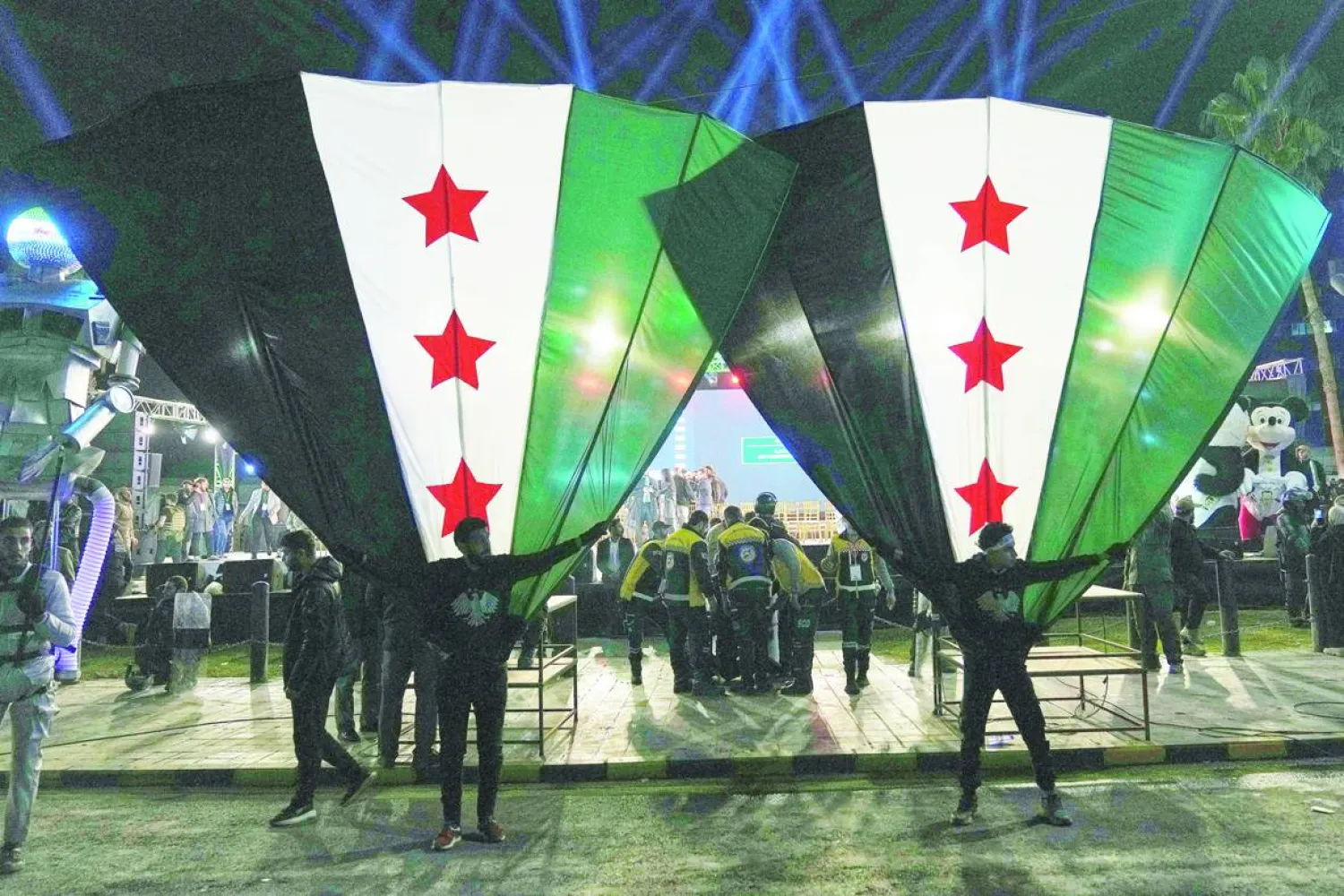 مواطنون سوريون يلوّحون بأعلامهم الوطنية خلال احتفالات الذكرى السنوية الأولى لإطاحة الرئيس السابق بشار الأسد في دمشق (أ.ب)