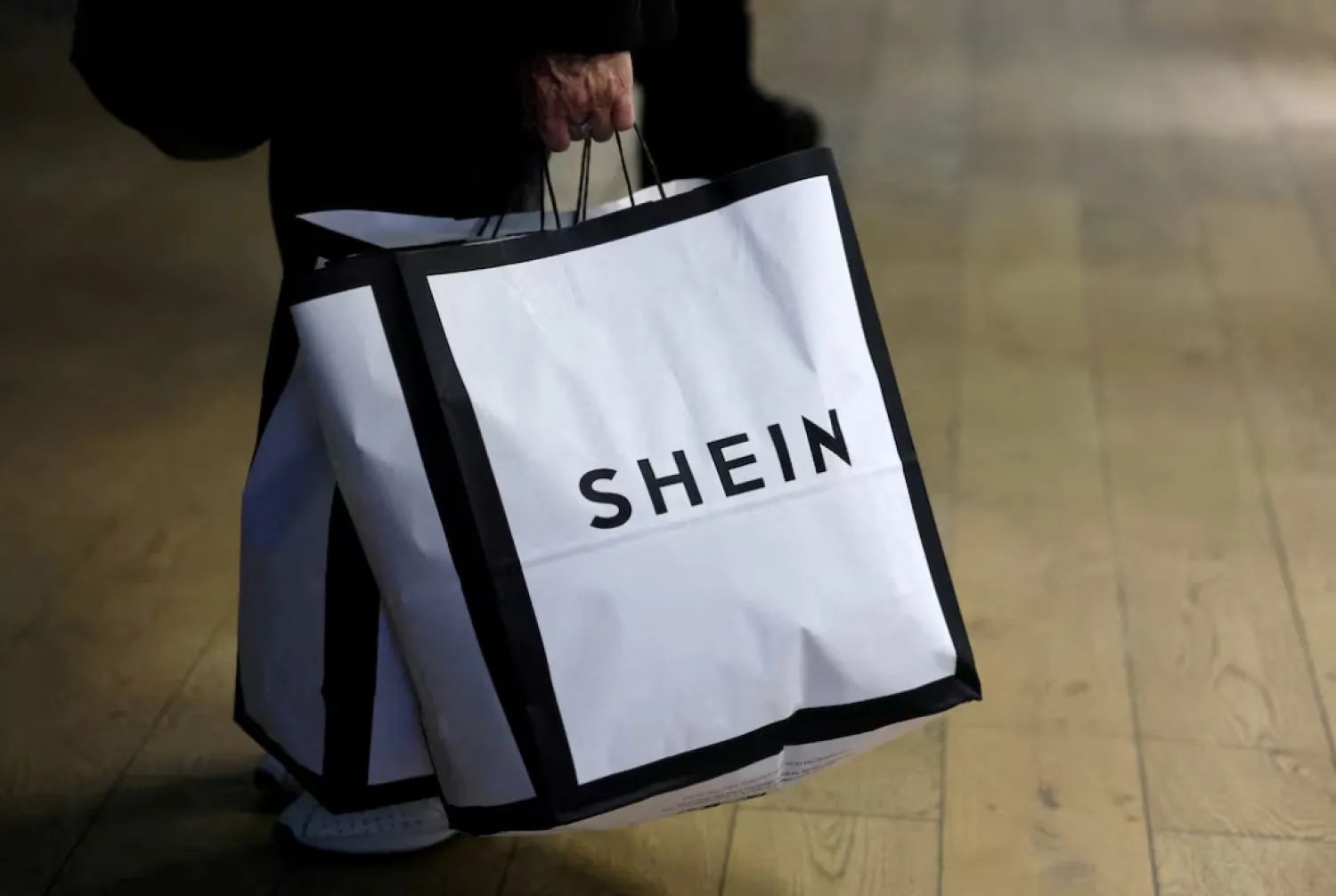 A customer holds shopping bags with a Shein logo in the first physical space of Chinese online fast-fashion retailer Shein on the day of its opening inside the Le BHV Marais department store, the Bazar de l'Hotel de Ville, in Paris, France, November 5, 2025. REUTERS/Sarah Meyssonnier/File Photo 