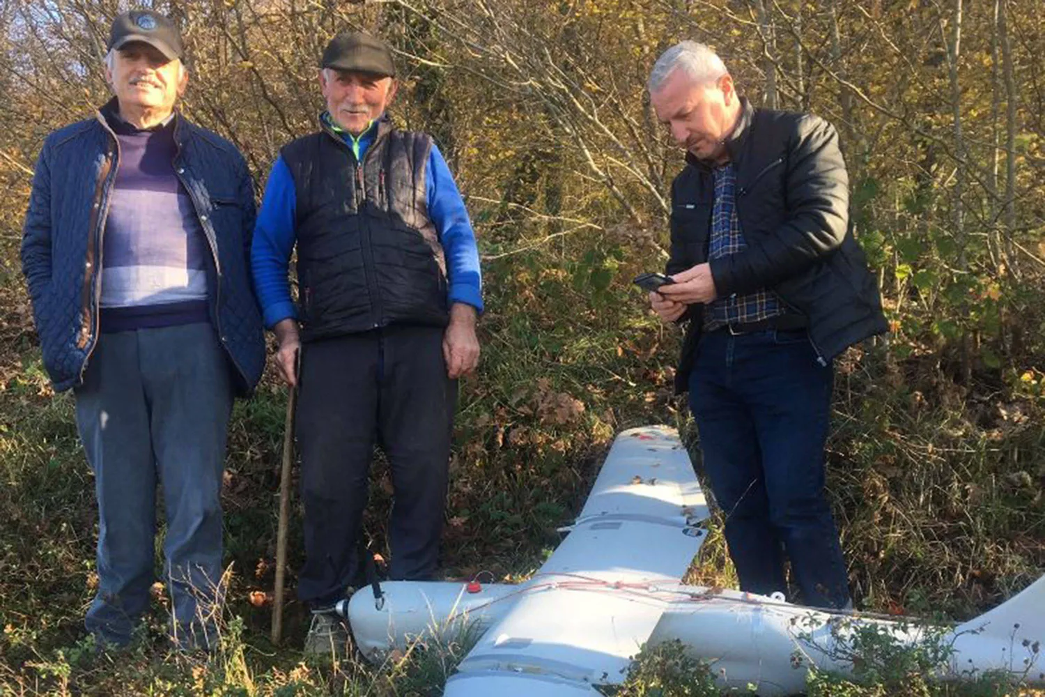 مجموعة من الأشخاص يقفون بجوار طائرة مسيرة يعتقد أنها روسية من نوع «أورلان - 10» سقطت في قوجه إيلي بشمال غرب تركيا (وكالة الأنباء التركية - أ.ف.ب)