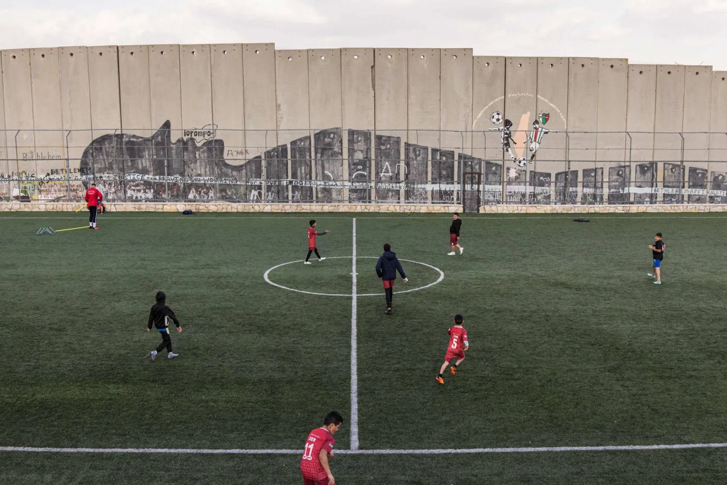  Displaced Palestinian youths take part in a training session at the Aida Refugee Camp's football pitch, next to the separation wall outside Bethlehem in the occupied West Bank, on December 16, 2025, a few weeks after an Israeli military decision to demolish the field. (AFP) 