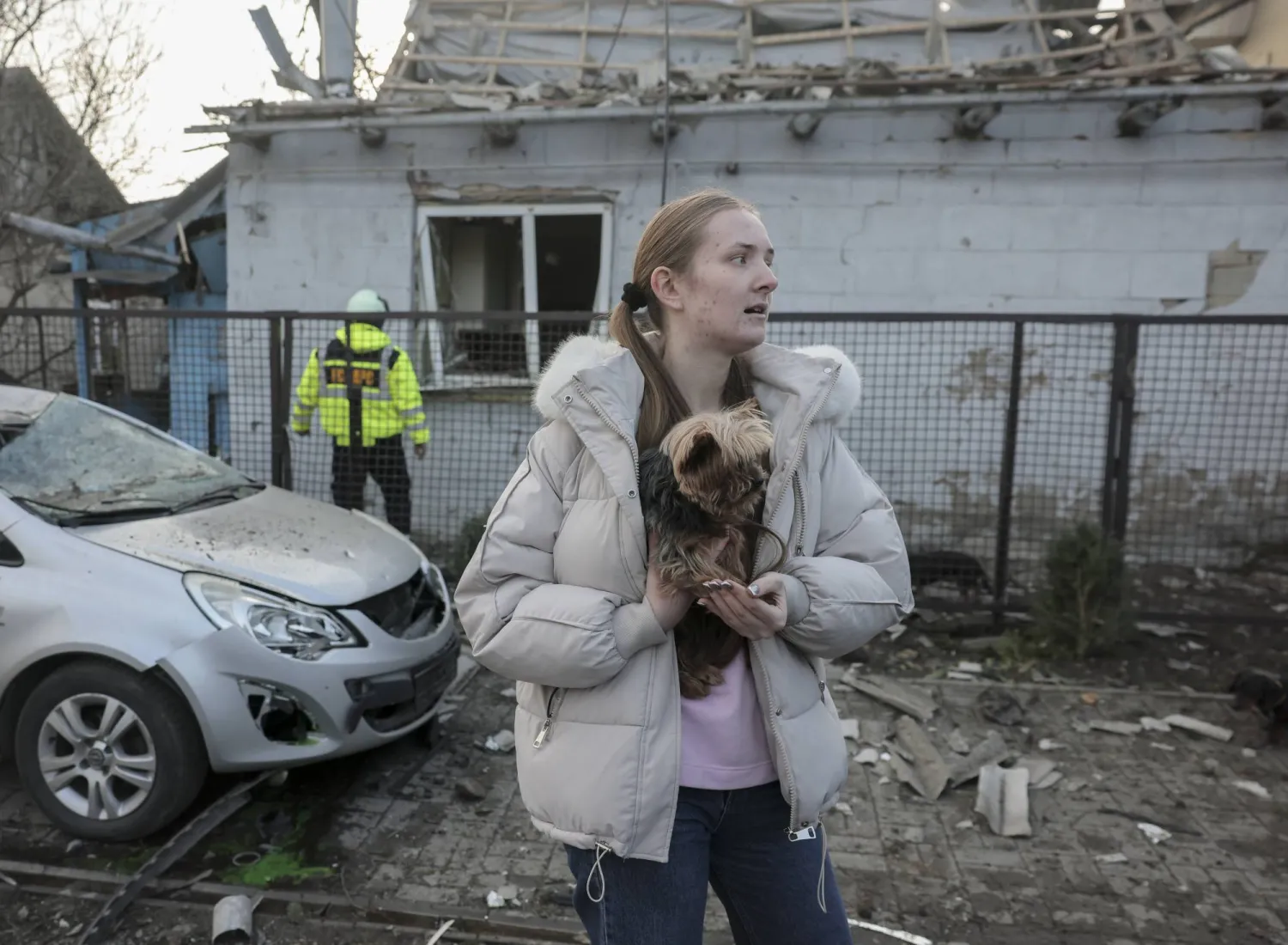امرأة محلية برفقة كلبها تتفاعل مع موقع غارة روسية على مبنى خاص في زابوروجيا (إ.ب.أ)