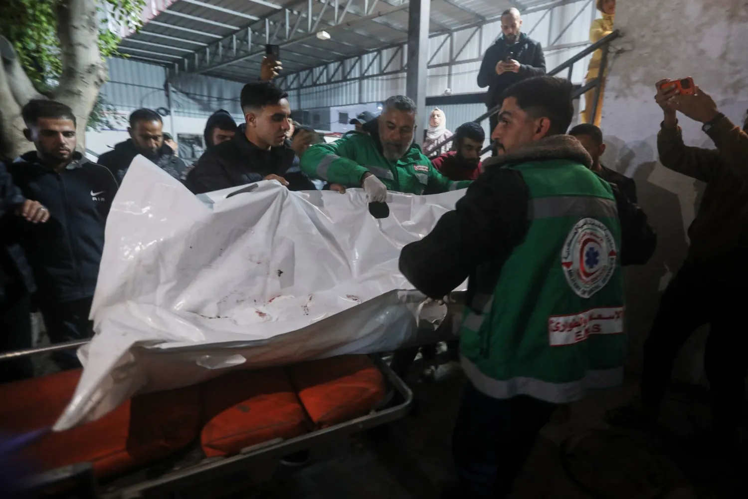 Palestinians carry the body of a person killed in an Israeli military strike as they arrive at Shifa Hospital in Gaza City, Friday, Dec. 19, 2025. (AP Photo/Yousef Al Zanoun)