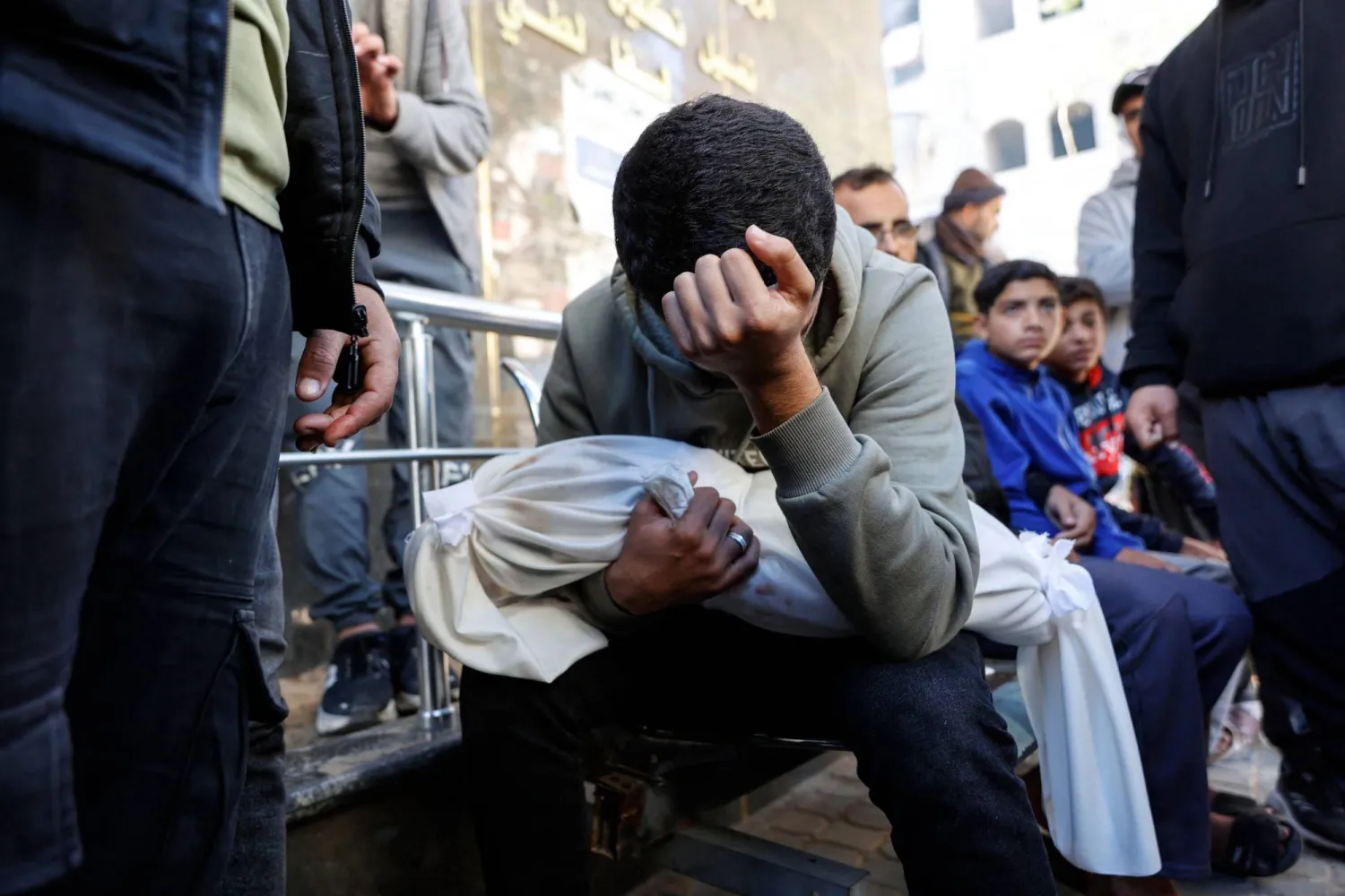 فلسطيني يبكي شقيقه البالغ من العمر 5 أشهر الذي قُتل بقصف إسرائيلي على حفل زفاف في مركز إيواء للنازحين بغزة السبت (أ.ف.ب)