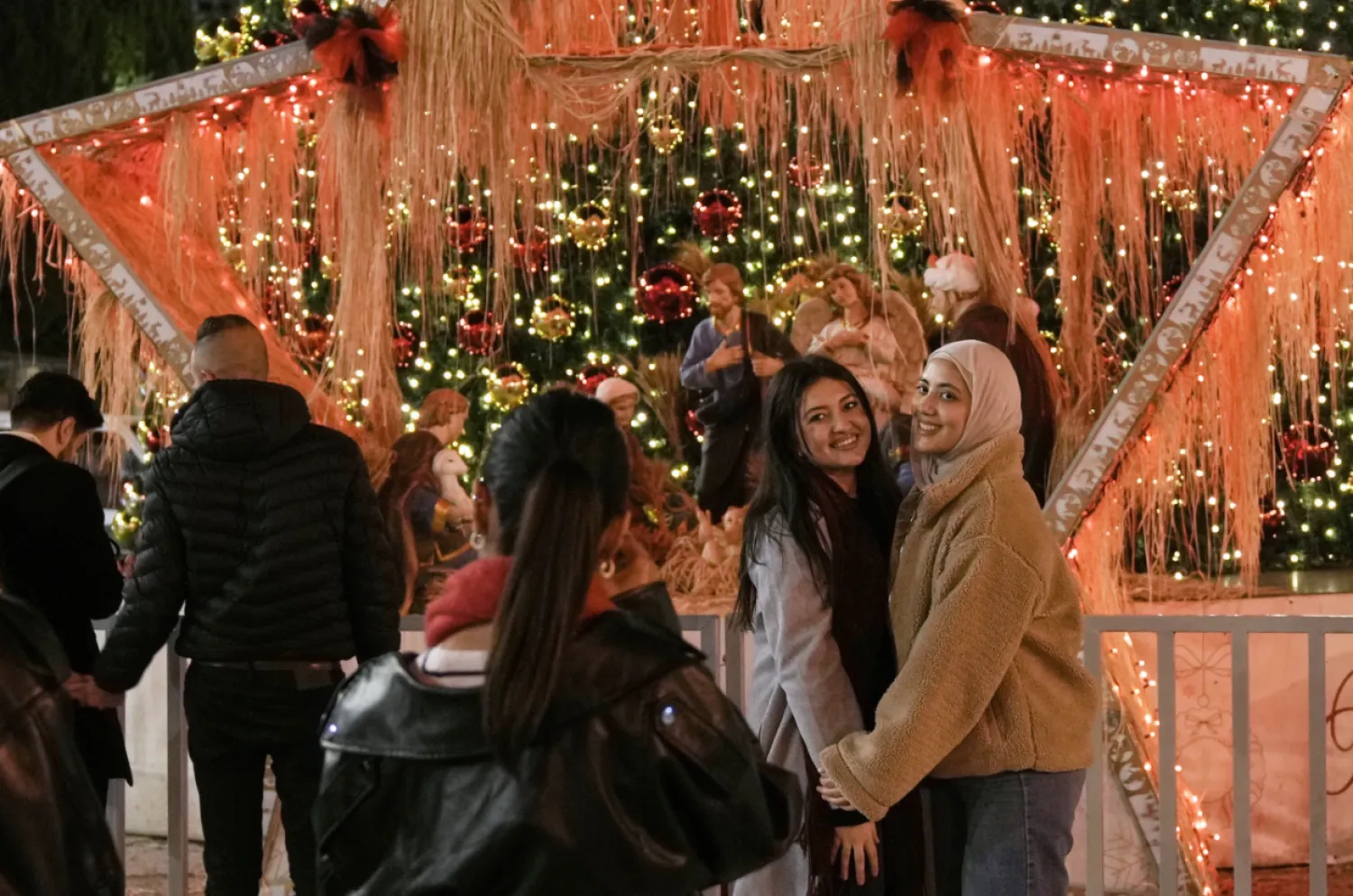 People pose for a picture in Manger Square in the West Bank city of Bethlehem, Tuesday, Dec. 16, 2025. (AP Photo/Mahmoud Illean)