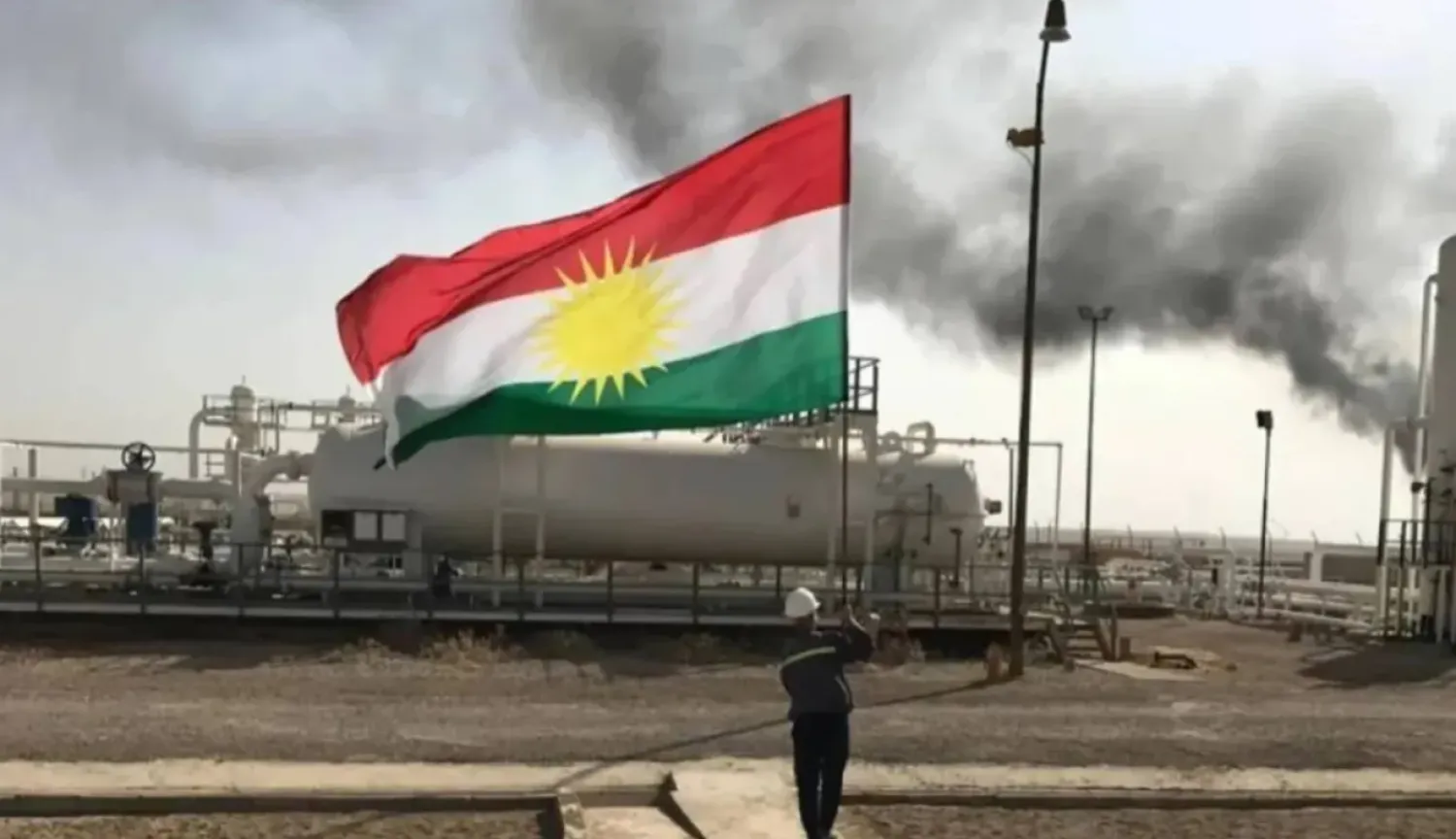 A staff at an oilfield holds the flag of Kurdistan. (X)
