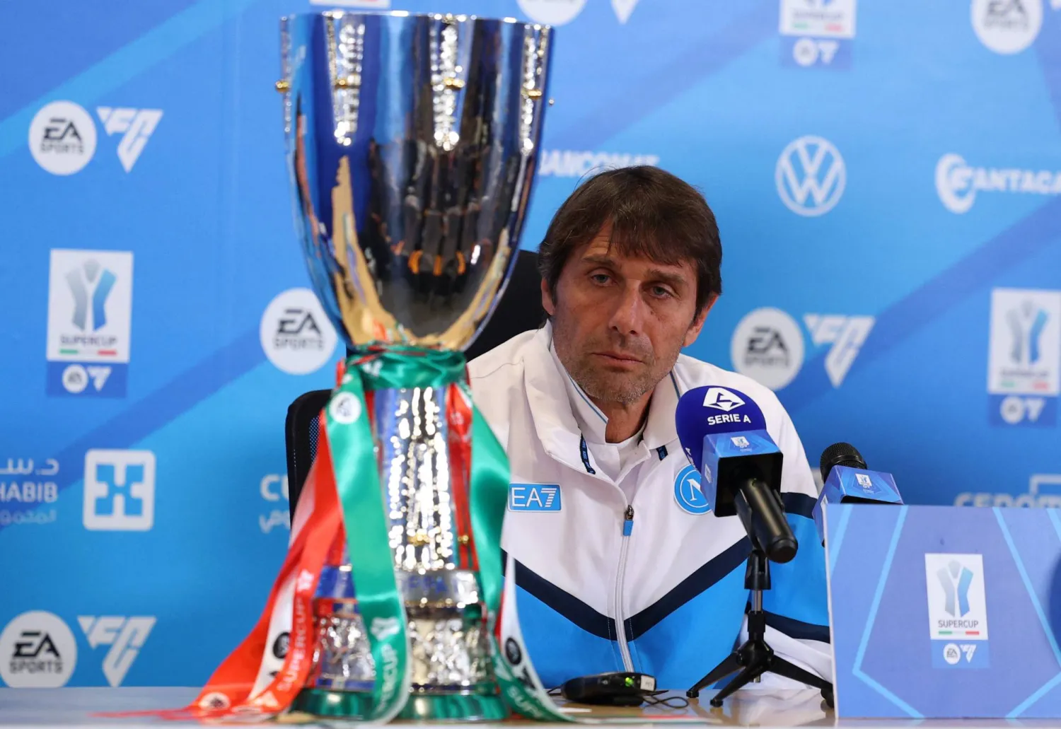كونتي خلال المؤتمر الصحافي وأمامه كأس السوبر الإيطالي (رويترز)