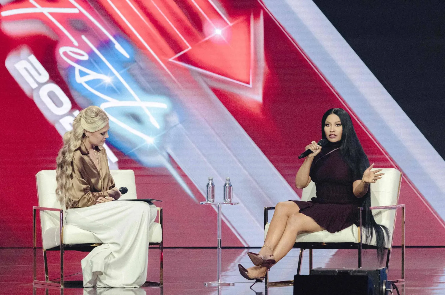 CEO and Chair of the Board of Turning Point USA Erika Kirk (L) listens to US rapper Nicki Minaj speak during Turning Point's annual AmericaFest conference in Phoenix, Arizona on December 21, 2025. (Photo by Olivier Touron / AFP)