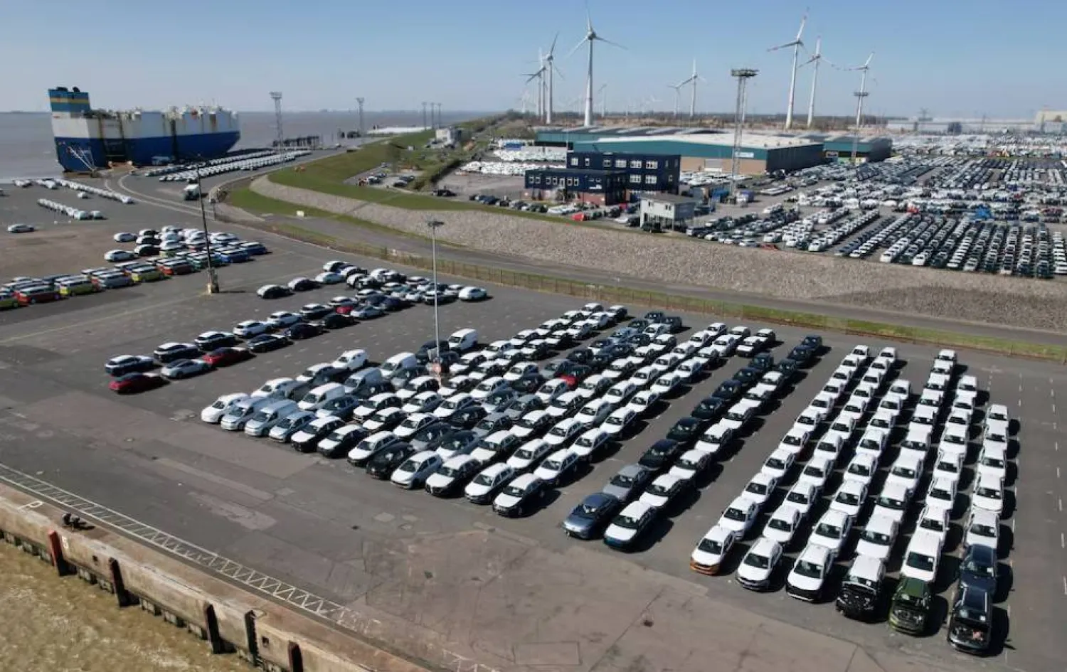 صورة جوية تُظهر سيارات مجموعة «فولكسفاغن» متجهة نحو شحنها على متن سفينة للتصدير إلى الولايات المتحدة بميناء إمدن (رويترز)