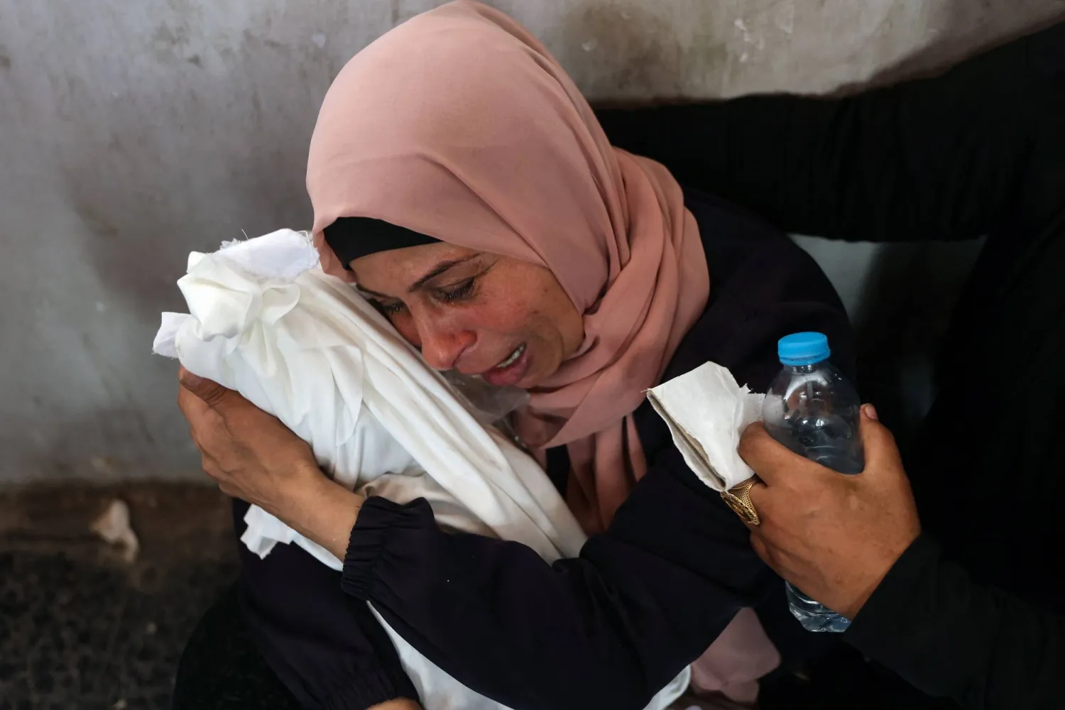 امرأة فلسطينية تبكي وهي تحمل طفلاً رضيعاً قُتل في غارة إسرائيلية بمدينة غزة (أ.ف.ب)