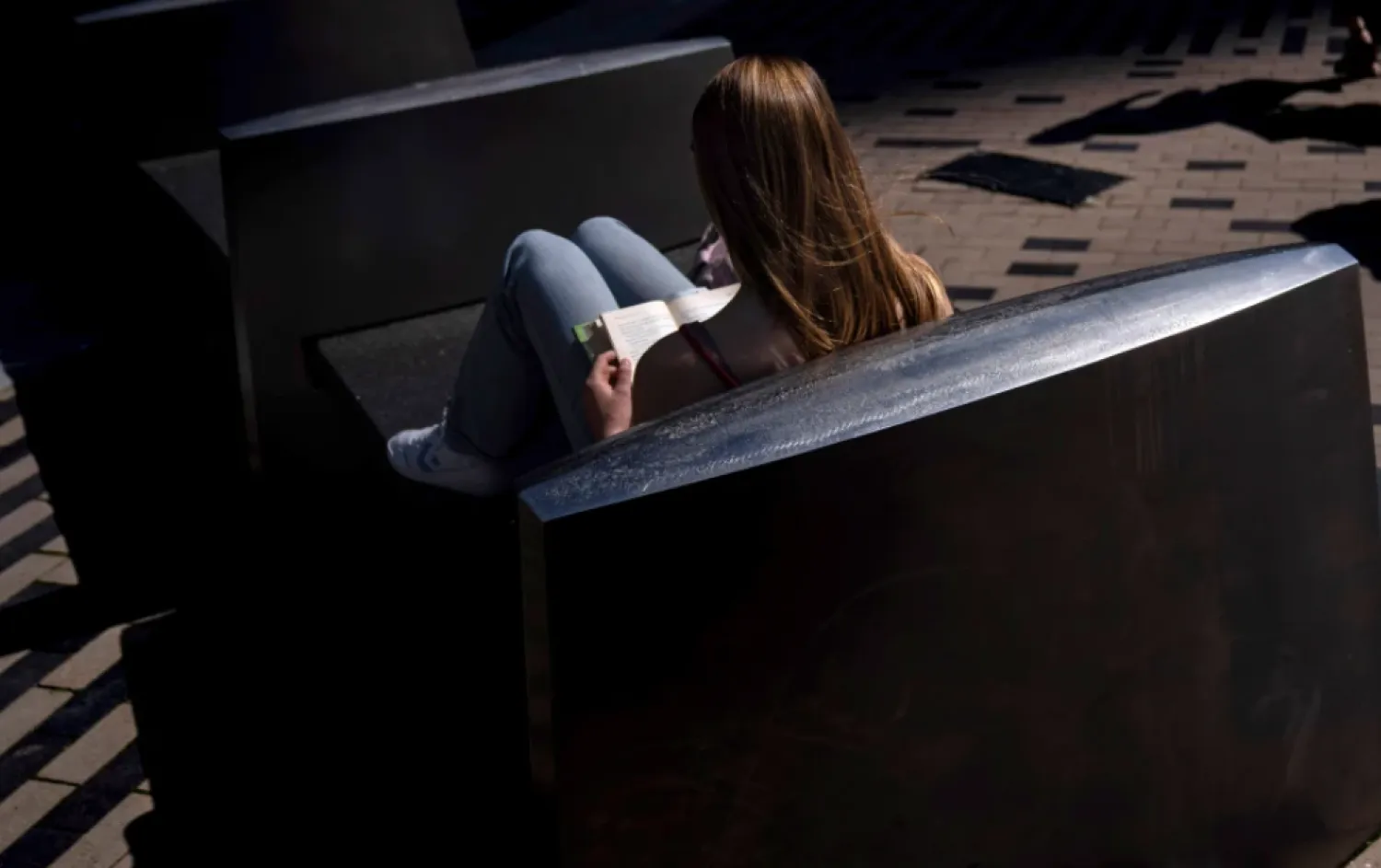A woman reads a book in the afternoon sun on a bench outside South Station in Boston, on Friday, May 31, 2024. (AP Photo/David Goldman, File)

