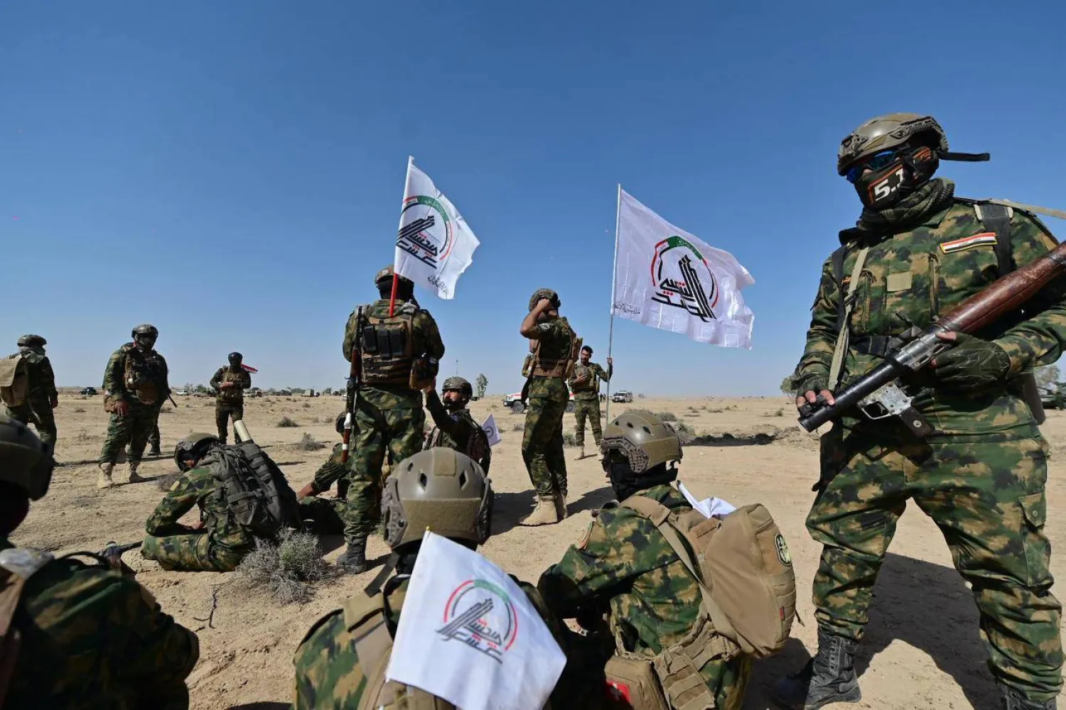 مقاتلون يرفعون شعار «الحشد الشعبي» خلال تدريبات عسكرية (أرشيفية-الحشد الشعبي)