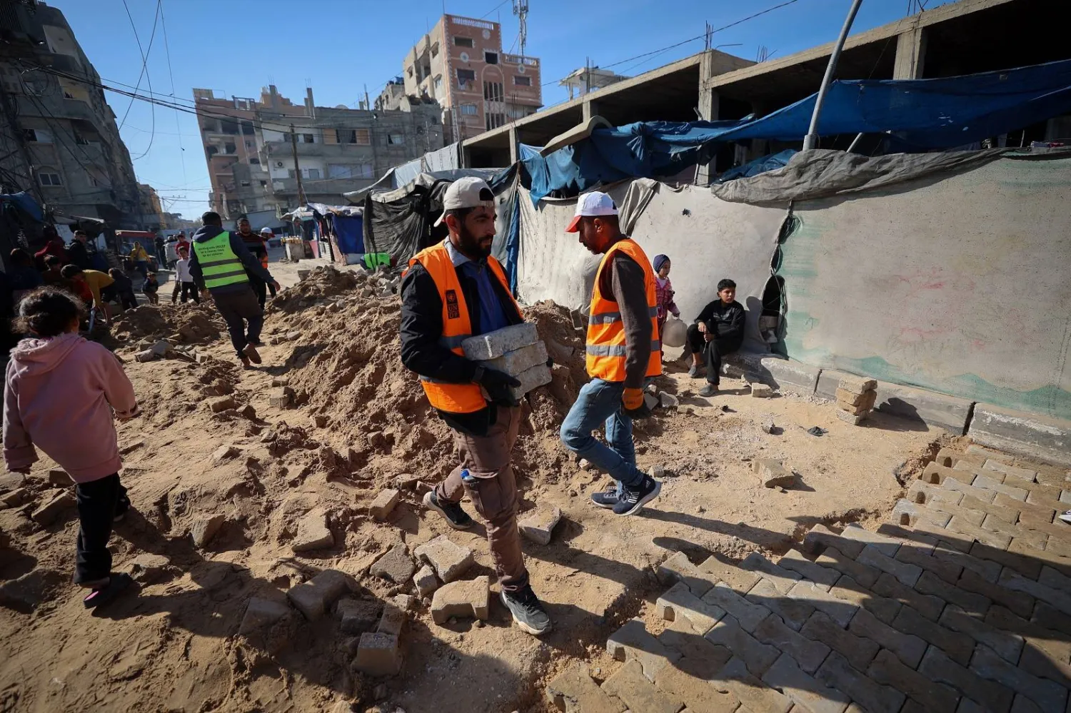 عمال البلدية الفلسطينيون يقومون بإصلاح طريق تضرر خلال الحرب في مخيم النصيرات للنازحين وسط قطاع غزة (أ.ف.ب)