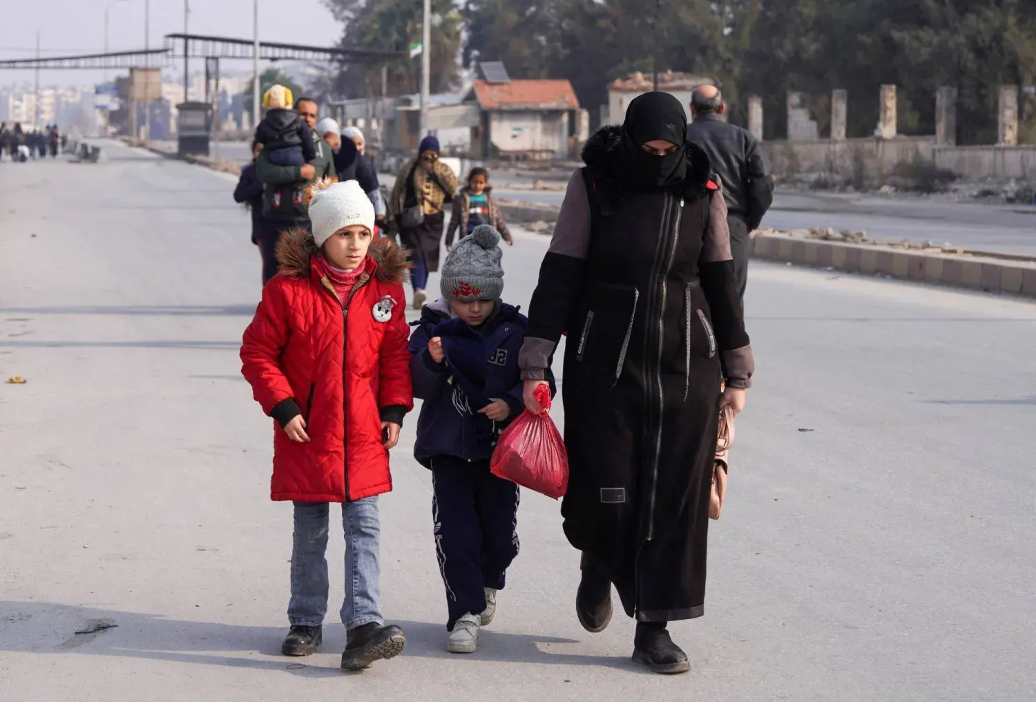 Şam ve SDG'nin pazartesi akşamı gerilimi azaltma konusunda anlaşmasının ardından Suriye, Halep'te iki çocuğuyla birlikte yürüyen bir kadın (Reuters)