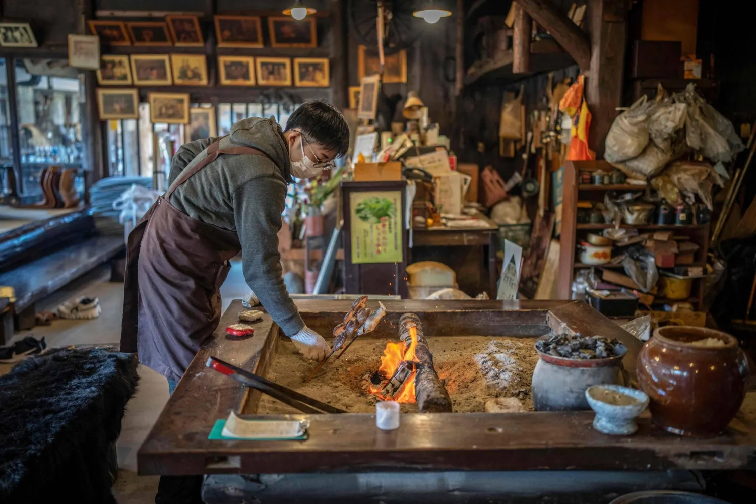 This picture taken on December 12, 2025 shows a member of staff grilling fish over a hearth at a restaurant which offers bear meat in Chichibu, Saitama prefecture. (AFP)