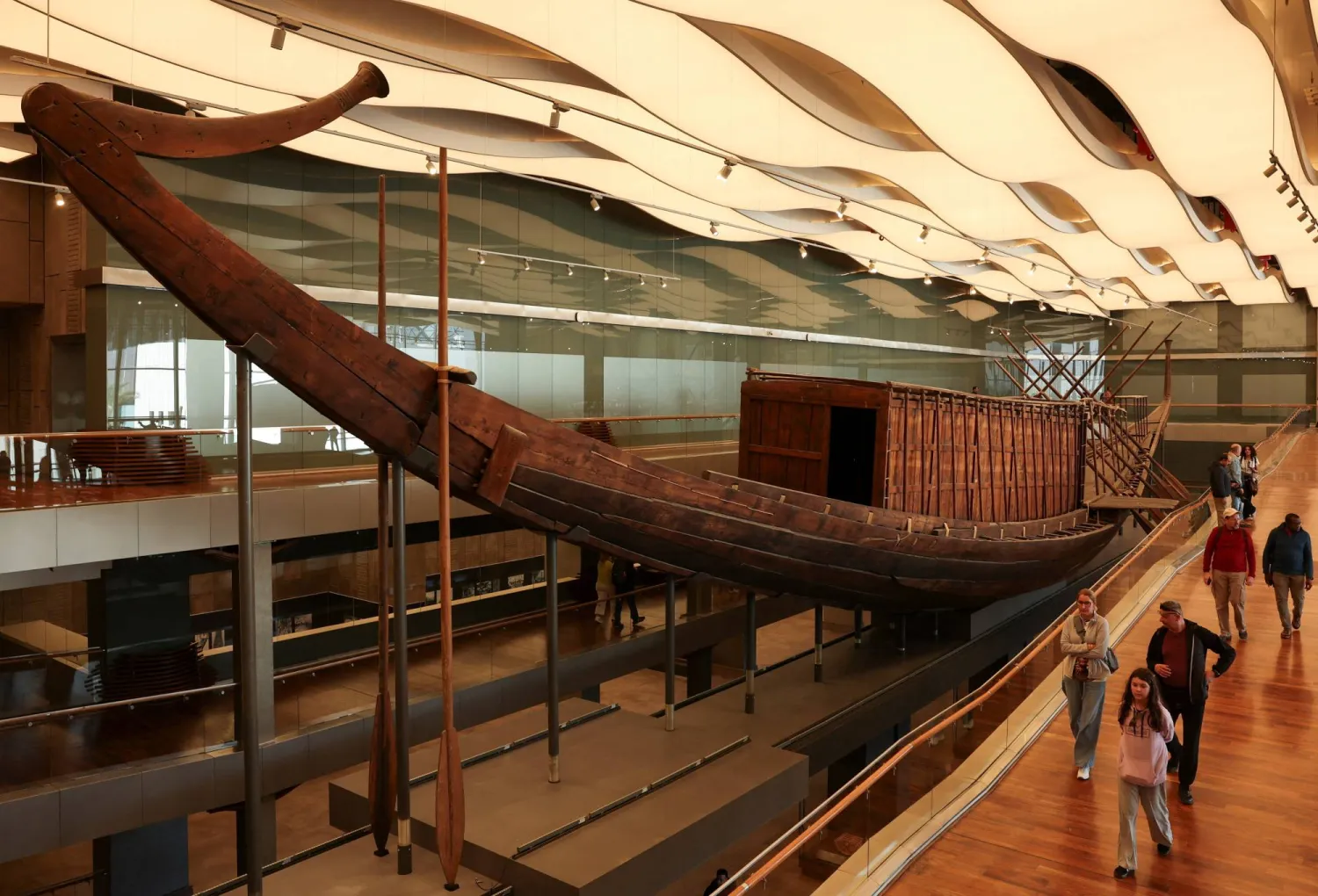 People walk next to King Khufu's boat gem, also known as the Solar Boat, as work to restore the second solar boat has started with wooden planks part of the 1,650-piece structure being installed on a metal frame through Egyptian-Japanese cooperation with two Japanese universities, marking the start of preparations for the second boat's public display at the Grand Egyptian Museum (GEM), near the Giza Pyramid Complex, in Giza, Egypt, December 23, 2025.