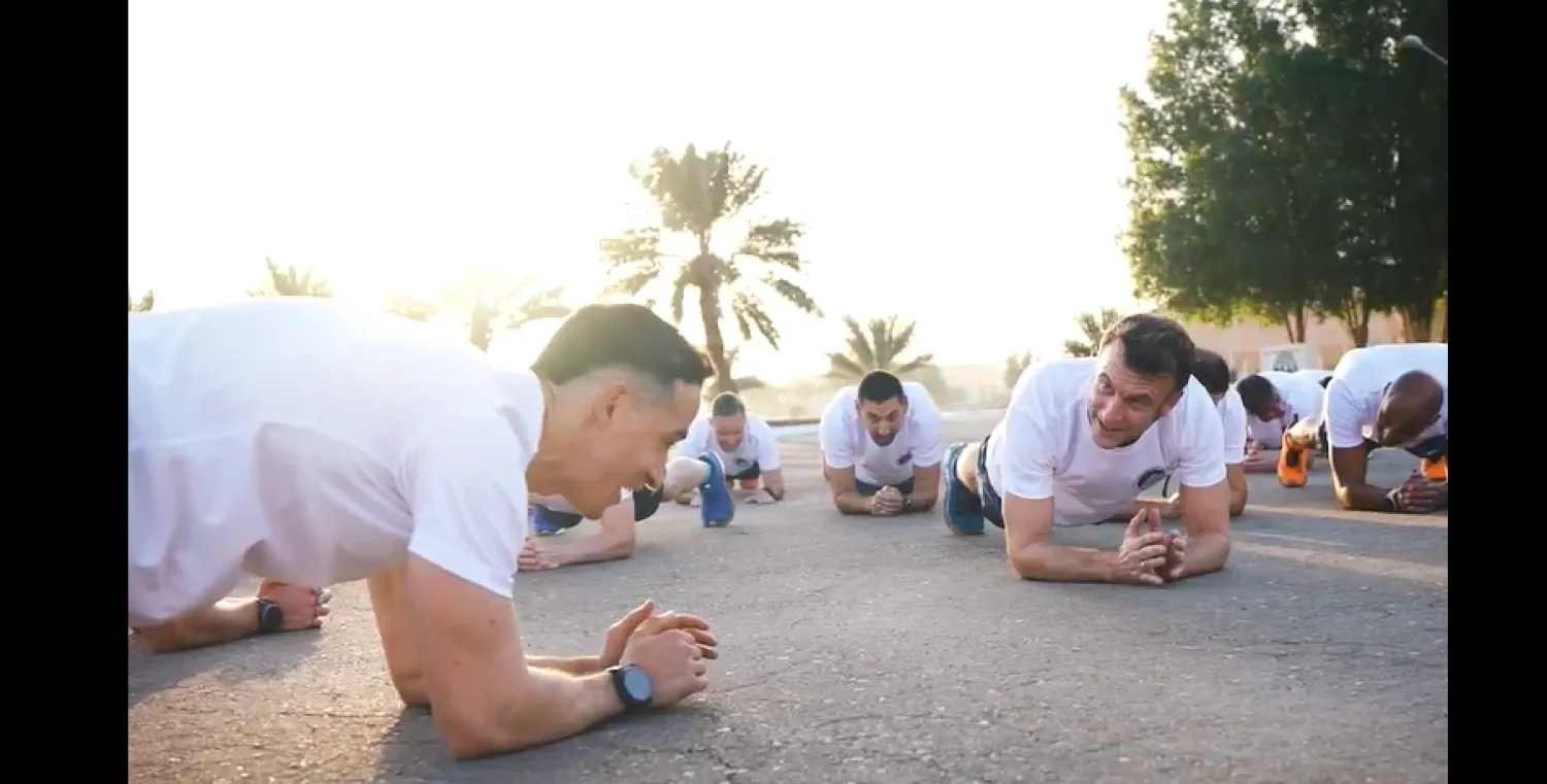 لقطة شاشة تُظهر الرئيس الفرنسي إيمانويل ماكرون (يمين) يقوم بتمارين رياضية برفقة جنود بلاده (إكس)