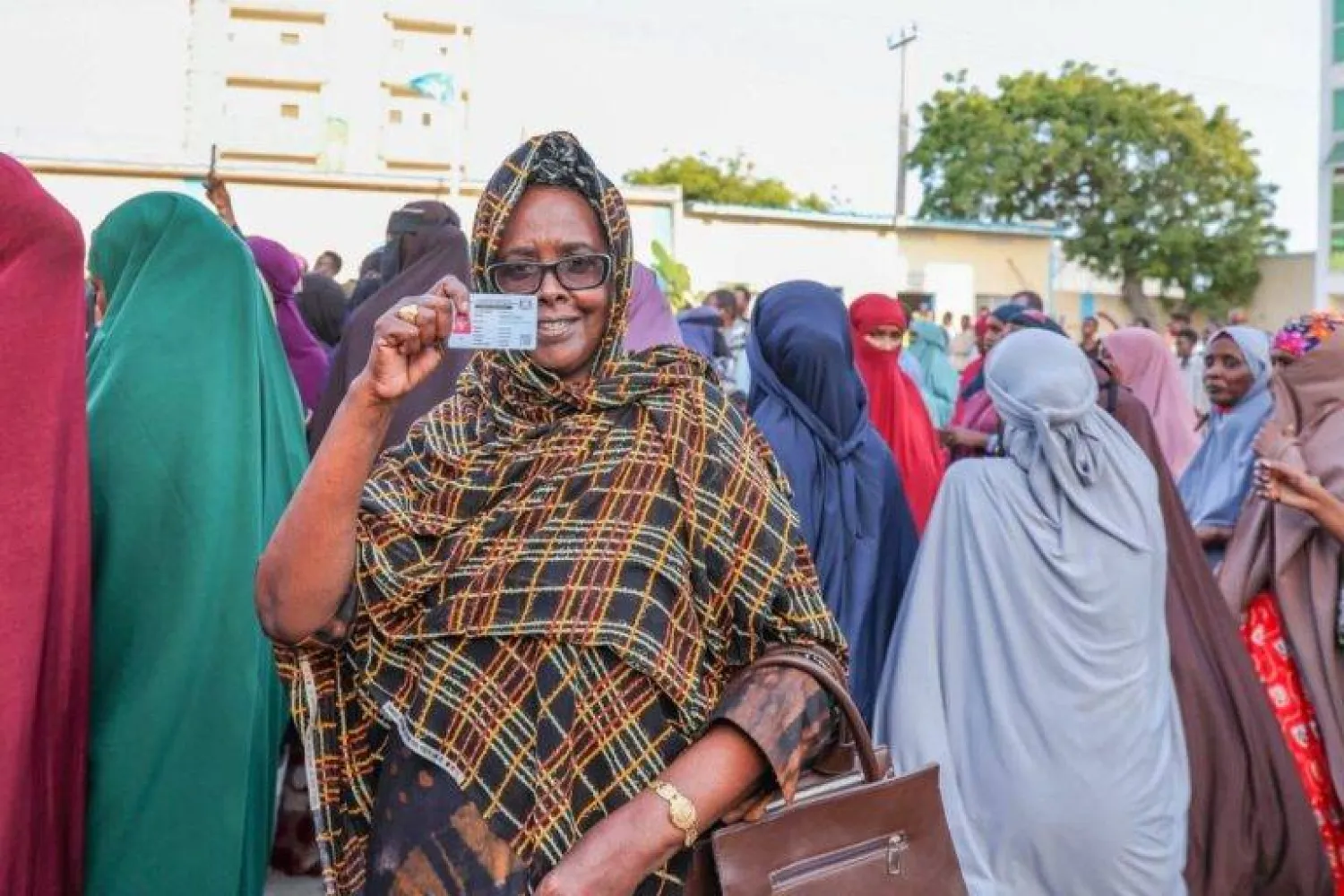 مواطنة صومالية ترفع بطاقتها الانتخابية خلال تجمع لدعم إجراء الانتخابات المحلية (وكالة الأنباء الصومالية)