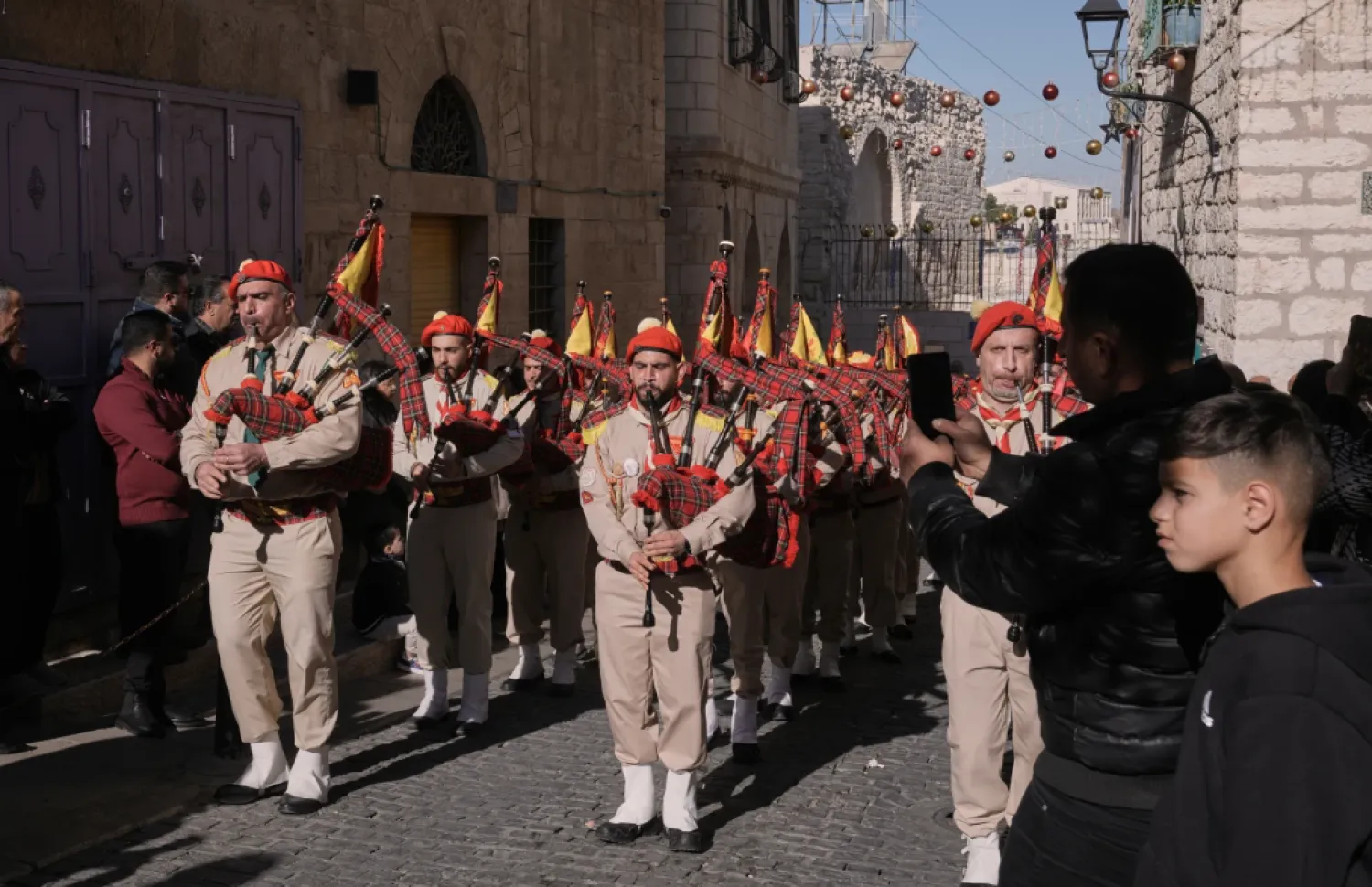  Palestinian scout bands parade toward the Manger Square near the Church of the Nativity, traditionally believed to be the birthplace of Jesus, on Christmas Eve, in the West Bank city of Bethlehem, Wednesday, Dec. 24, 2025. (AP Photo/Mahmoud Illean)


