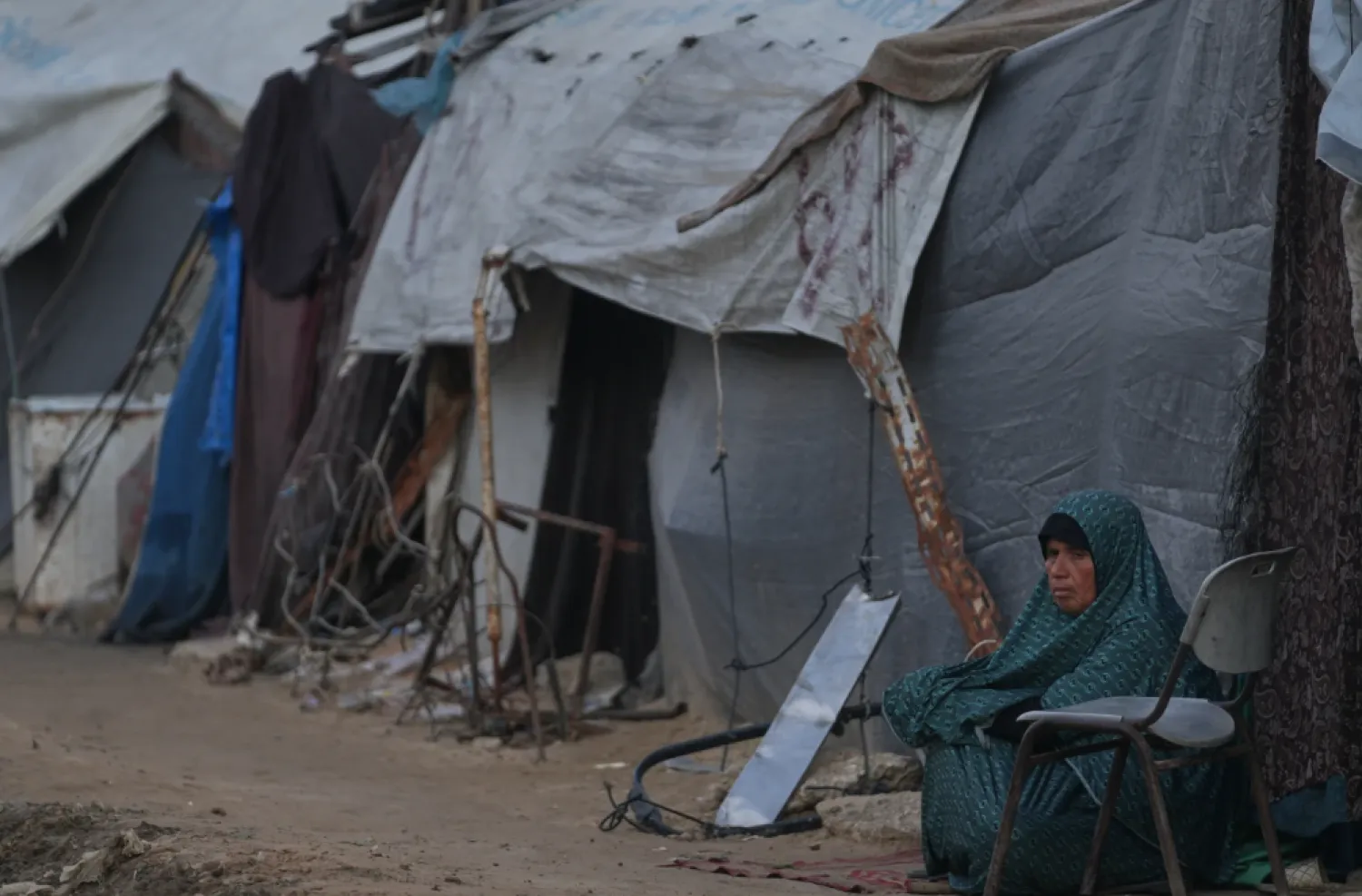 A woman sits next to her tent on an alley of a makeshift tent camp for displaced Palestinians in Deir al-Balah, central Gaza Strip, Tuesday, Dec. 23, 2025. (AP Photo/Abdel Kareem Hana)