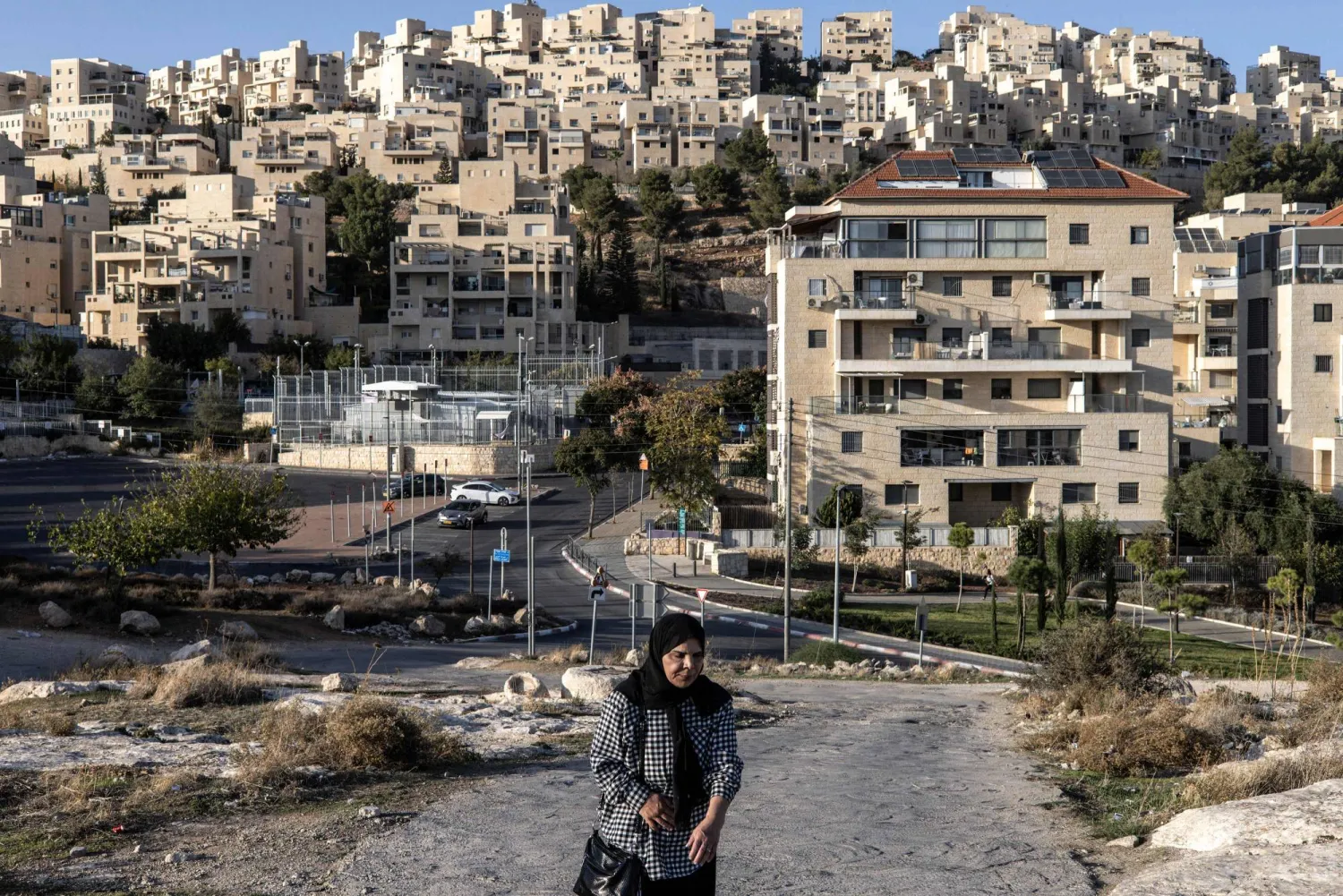 A Palestinian woman walks past the Israeli settlement of Har Homa, southeast of Jerusalem, on November 21, 2025. (AFP)