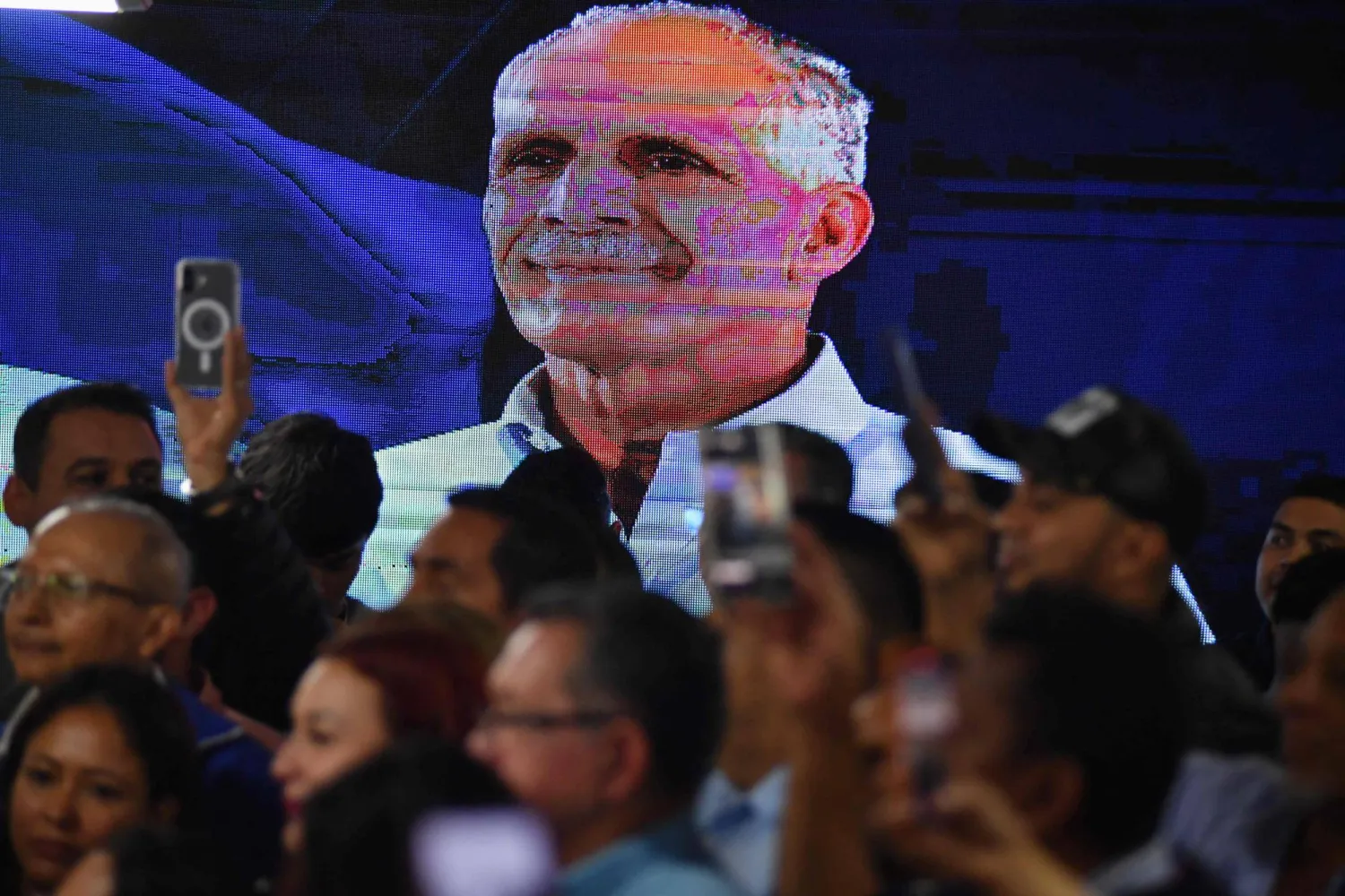 شاشة تعرض صورةً لنصري عصفورة وسط أنصاره (أ.ف.ب)
