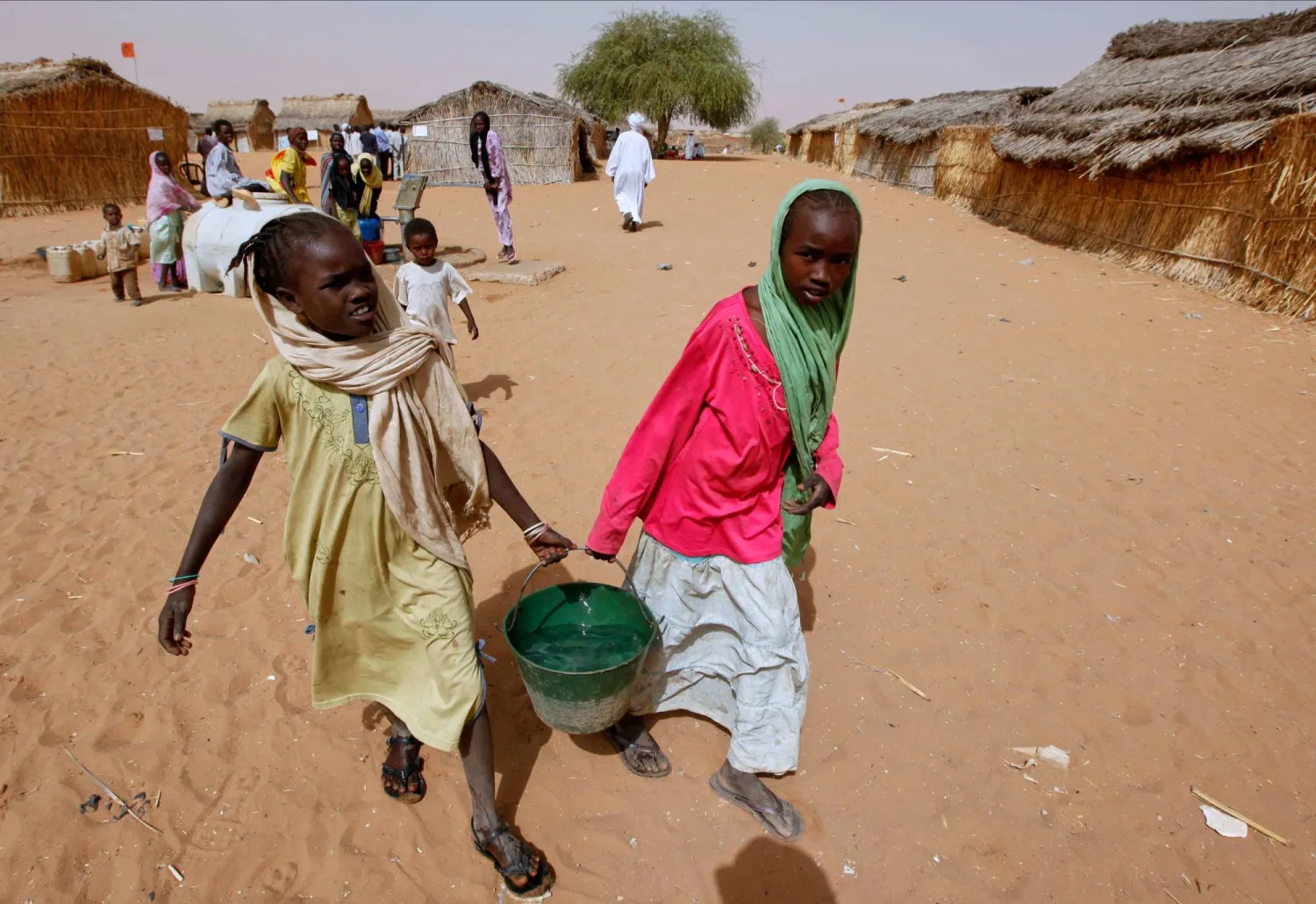 Sudanese refugee girls carry water supplies near a polling station in the refugee camp of Zamzam, on the outskirts of el-Fasher, Darfur, Sudan, on April 13, 2010. (AP)