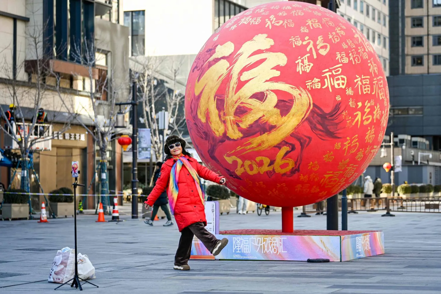 سيدة تستعد لالتقاط صورة تذكارية مع زينة العام الجديد في أحد الشوارع التجارية بالعاصمة الصينية بكين (أ.ف.ب)