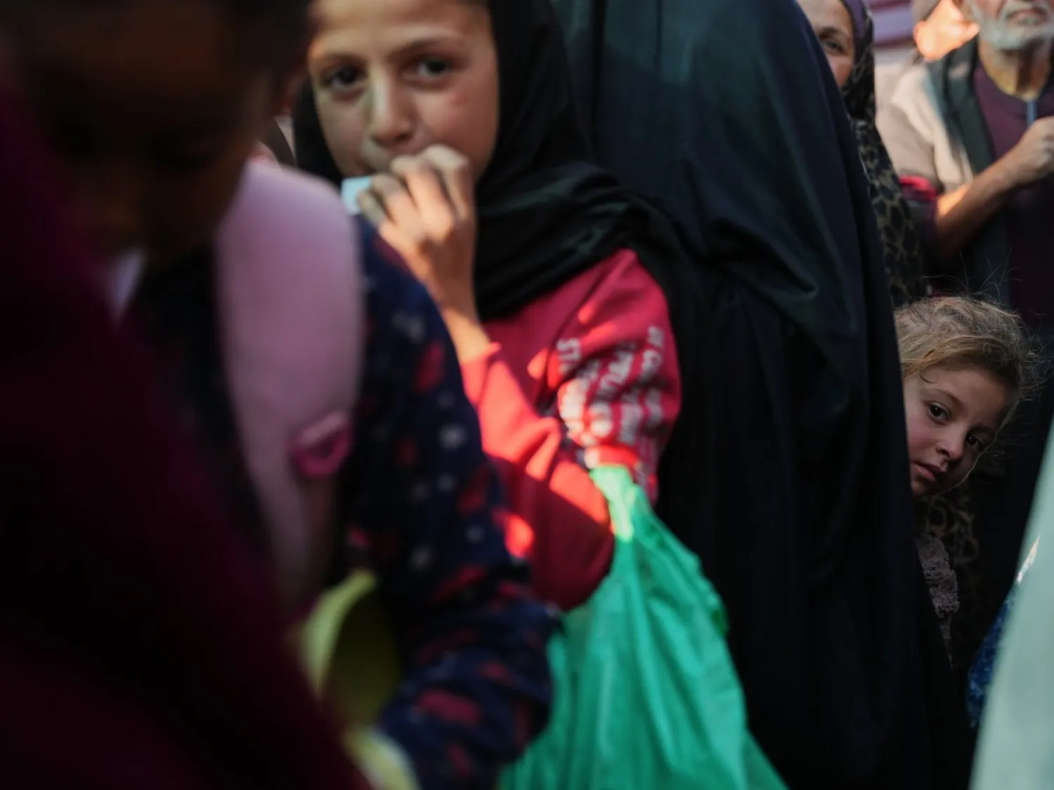 فتاة فلسطينية تقف بين صفوف المنتظرين لتلقي طعام من مطبخ خيري في دير البلح وسط غزة يوم الخميس (أ.ب)