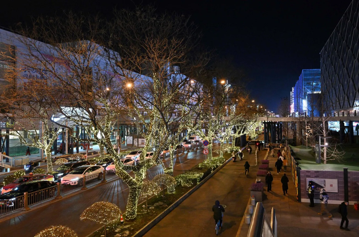 People walk next to shopping centers in Beijing on December 19, 2025. (AFP)