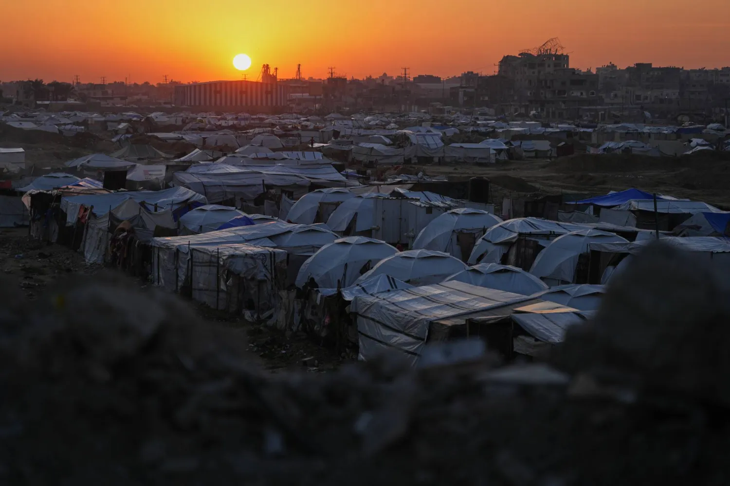 The sun sets behind a makeshift tent camp for displaced Palestinians set up in an area of al-Bureij camp, in the central Gaza Strip, Wednesday, Dec. 24, 2025. (AP)