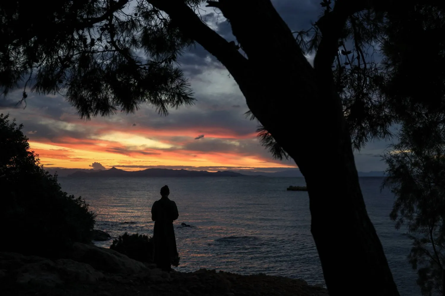 A woman looks at sunset on Christmas Day, at a southern coastal suburb in Athens, Greece, December 25, 2025. REUTERS/Louisa Gouliamaki