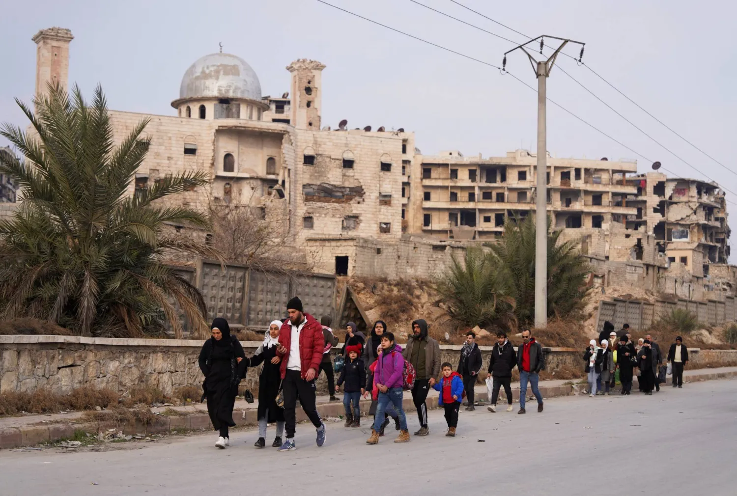 أشخاص يسيرون على طول طريق في حلب بعد موافقة «قسد» على خفض التصعيد الأسبوع الماضي (رويترز)