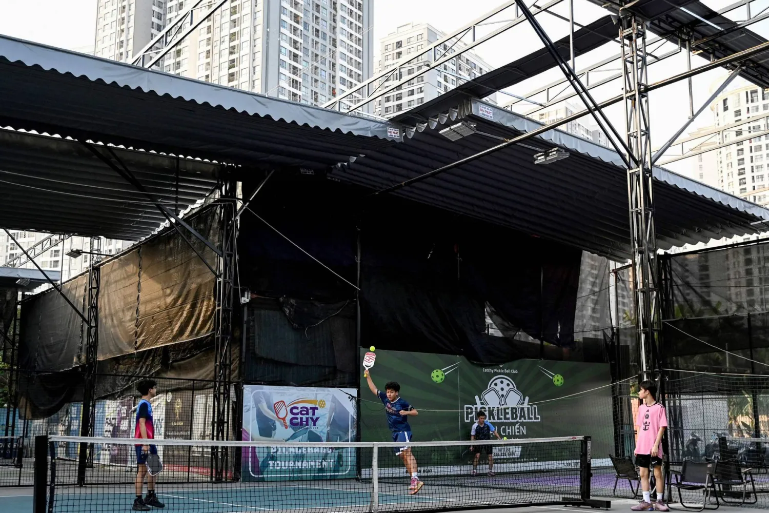 This photo taken on December 23, 2025, shows children playing pickleball in the playground of a residential area in Hanoi. (Photo by Nhac NGUYEN / AFP)