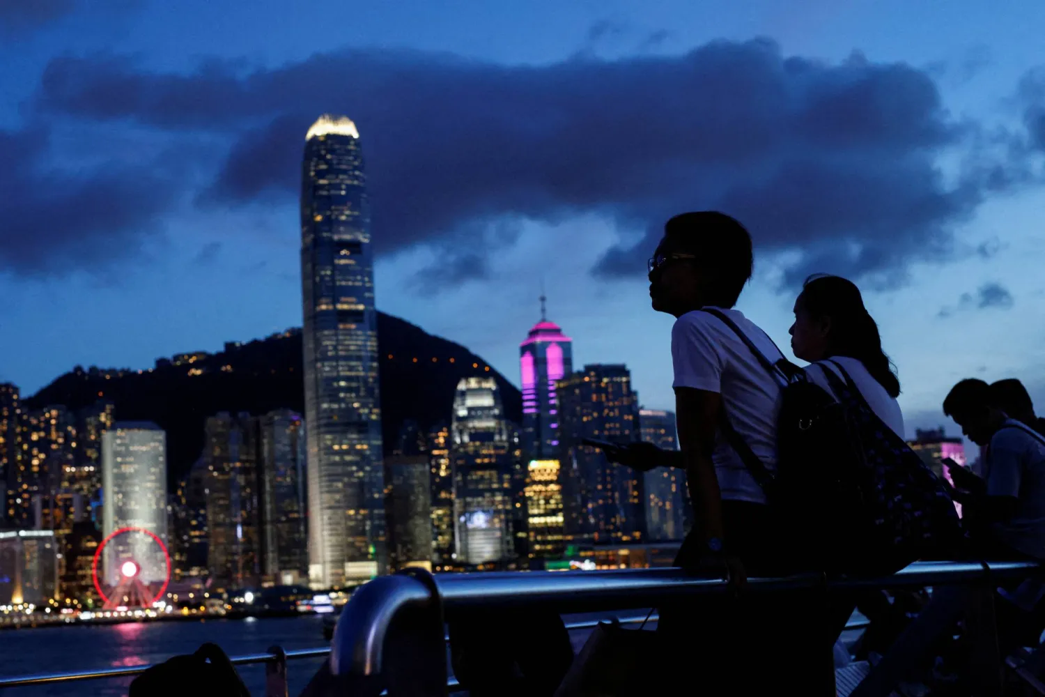 FILE PHOTO: Tourists relax on the waterfront in front of Victoria Harbour, with the iconic skyline buildings as a backdrop, in Hong Kong, China June 28, 2023. REUTERS/Tyrone Siu/File Photo