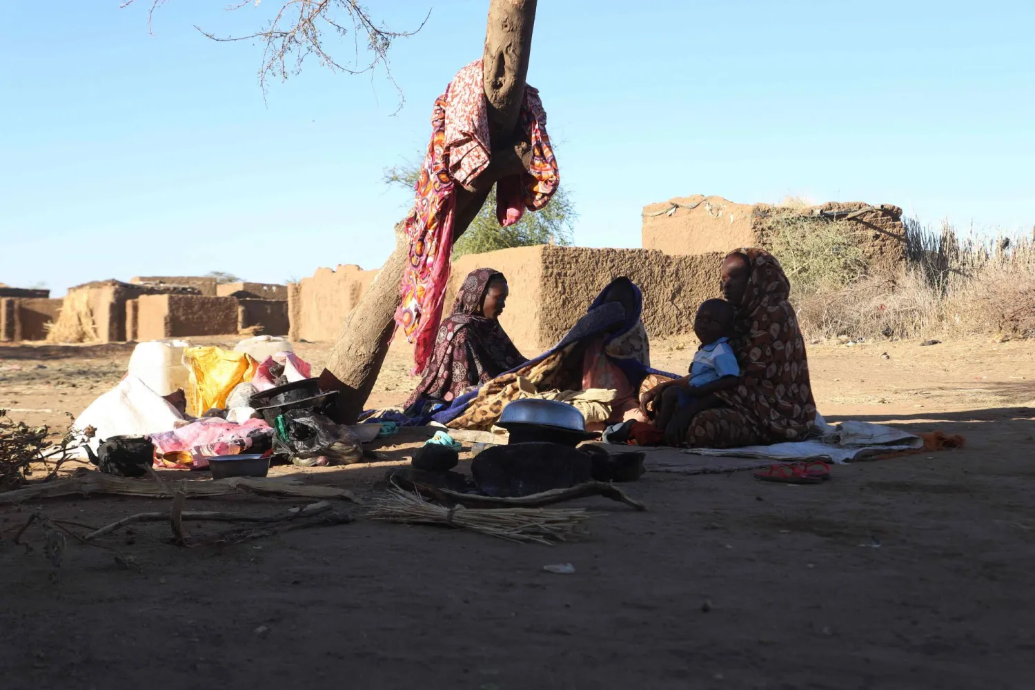 Sudanese displaced people who left El Fasher after its fall, sit in the shade in Tawila at the Rwanda camp reception point on December 17, 2025. (Photo by AFP)