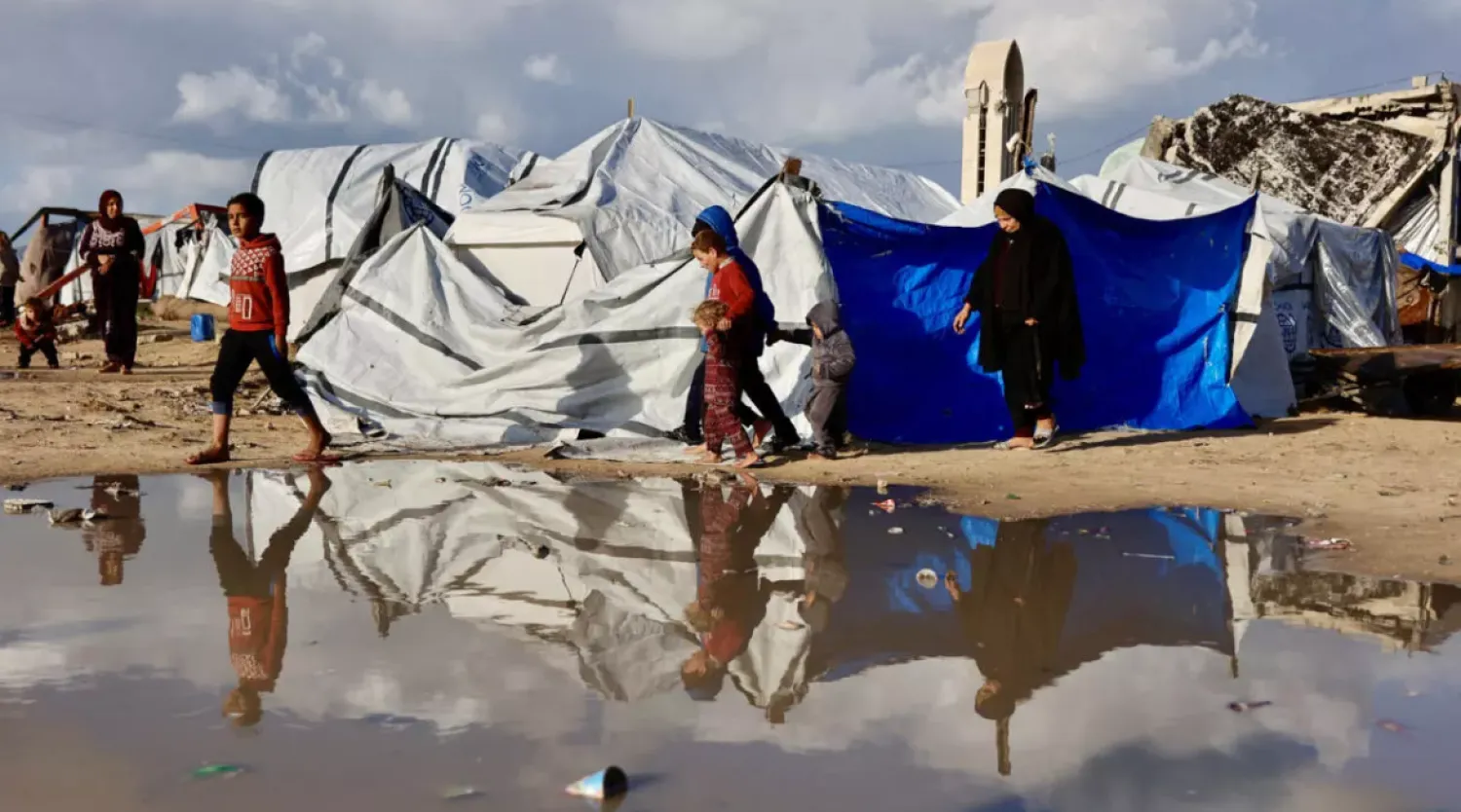Displaced Palestinians walk past a large pool of standing water in Gaza City. Heavy winter rains have have made an already precarious life worse for displaced Gazans © Omar AL-QATTAA / AFP
