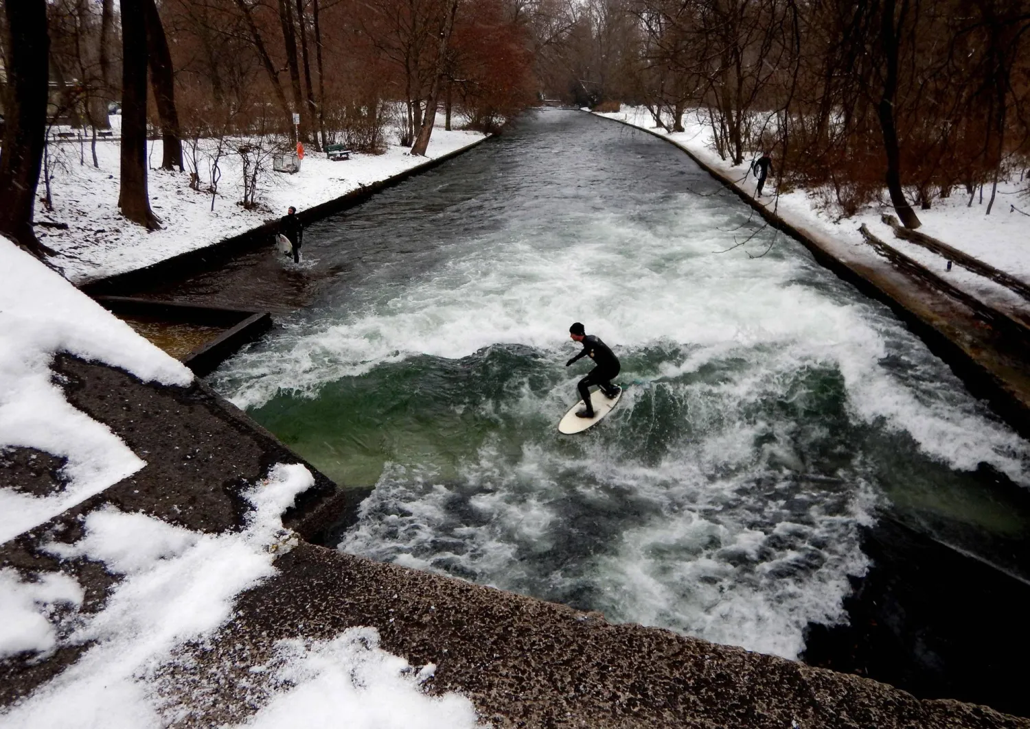 (FILES) Surfers ride the Eisbach (ice creek) wave during freezing conditions on the Isar River in the English Garden in Munich, southern Germany on January 4, 2017. (Photo by Mark RALSTON / AFP)